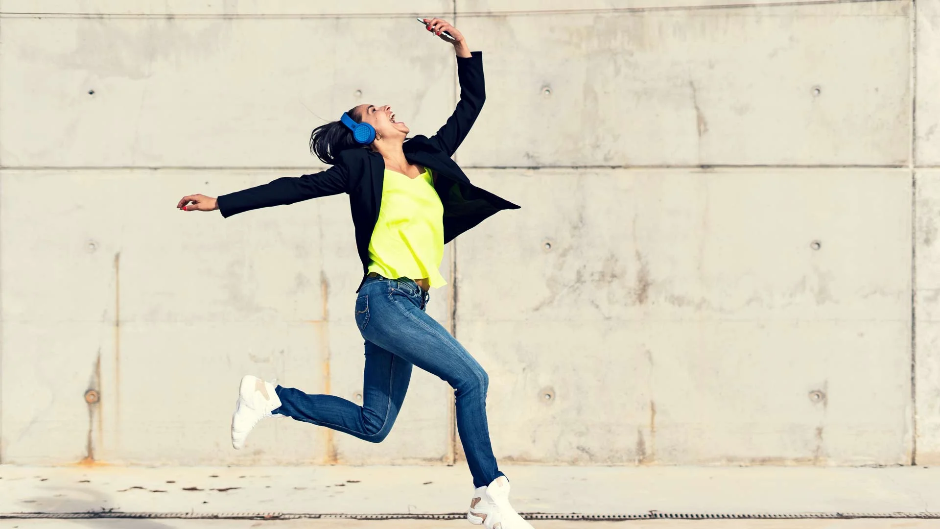 Person dancing in the street with bluetooth headphones.