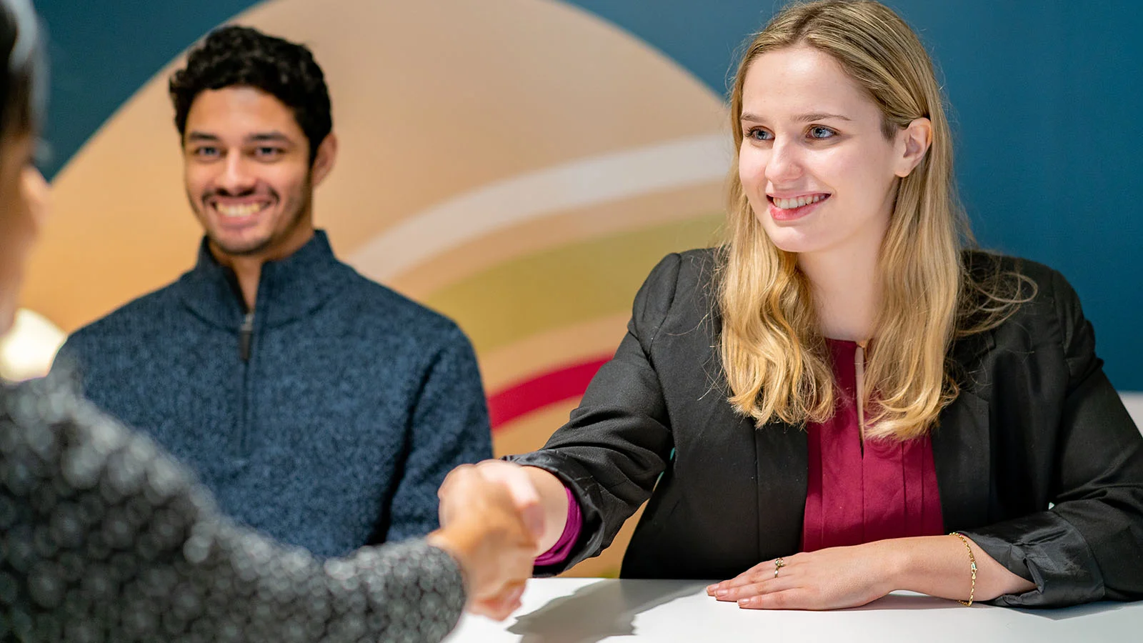 Woman shaking hands with employer, having just negotiated her contract.