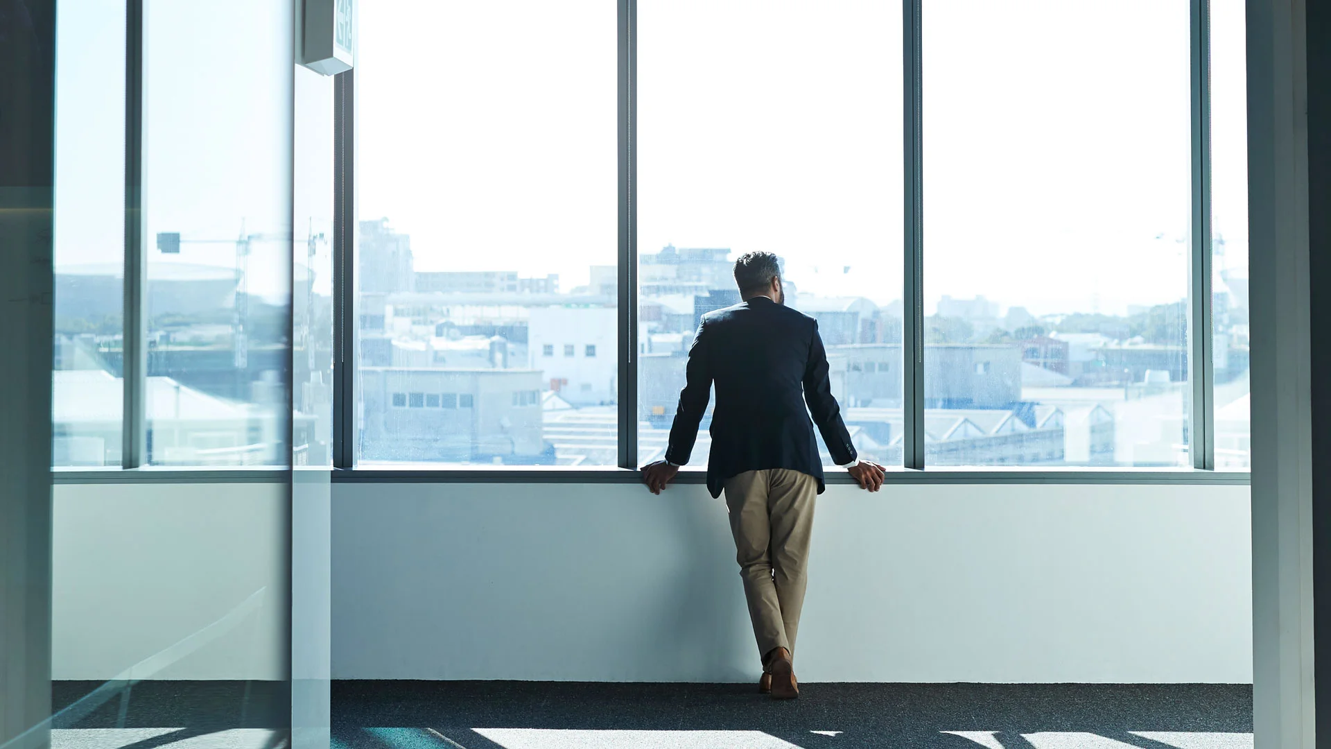 Businessman staring out of the window across a city skyline.