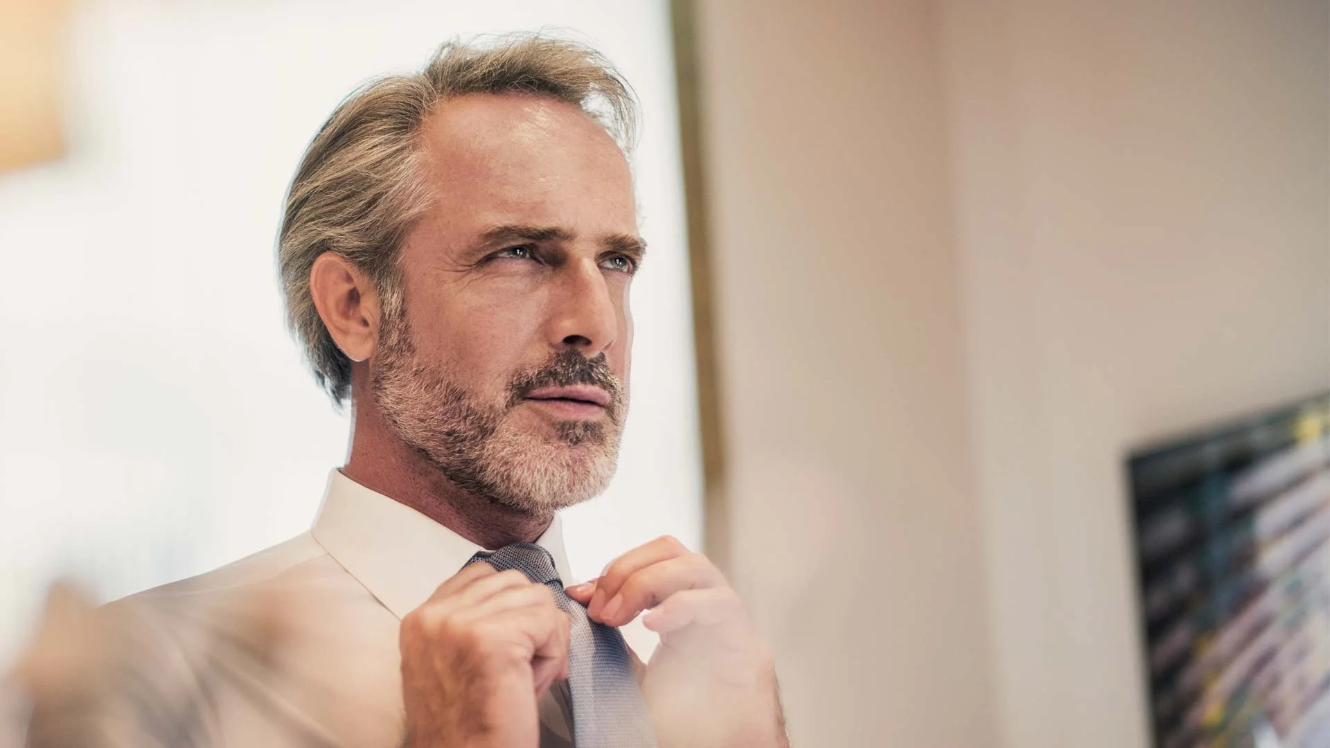 Middle aged man getting dressed in front of an interview in the outfit he will wear to his job interview.