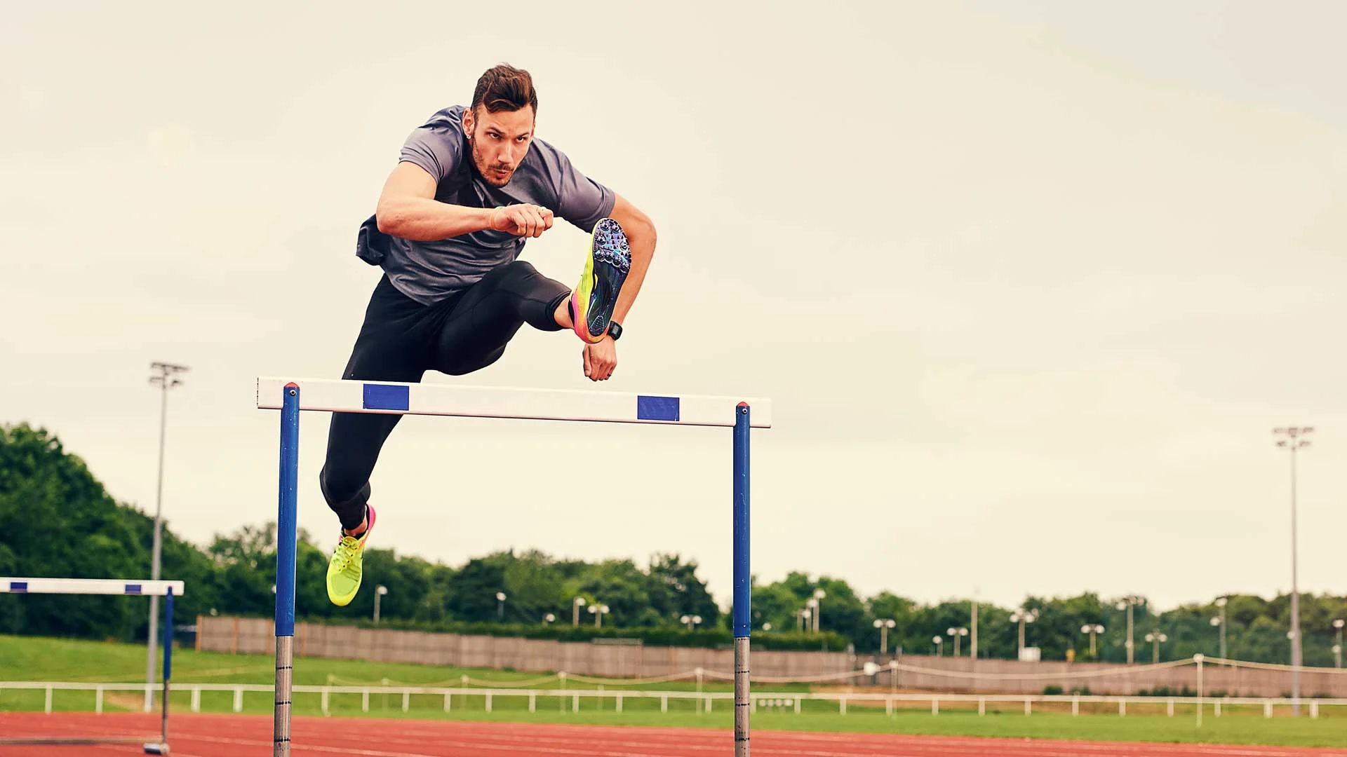 An athlete jumping over a hurdle on a running track.
