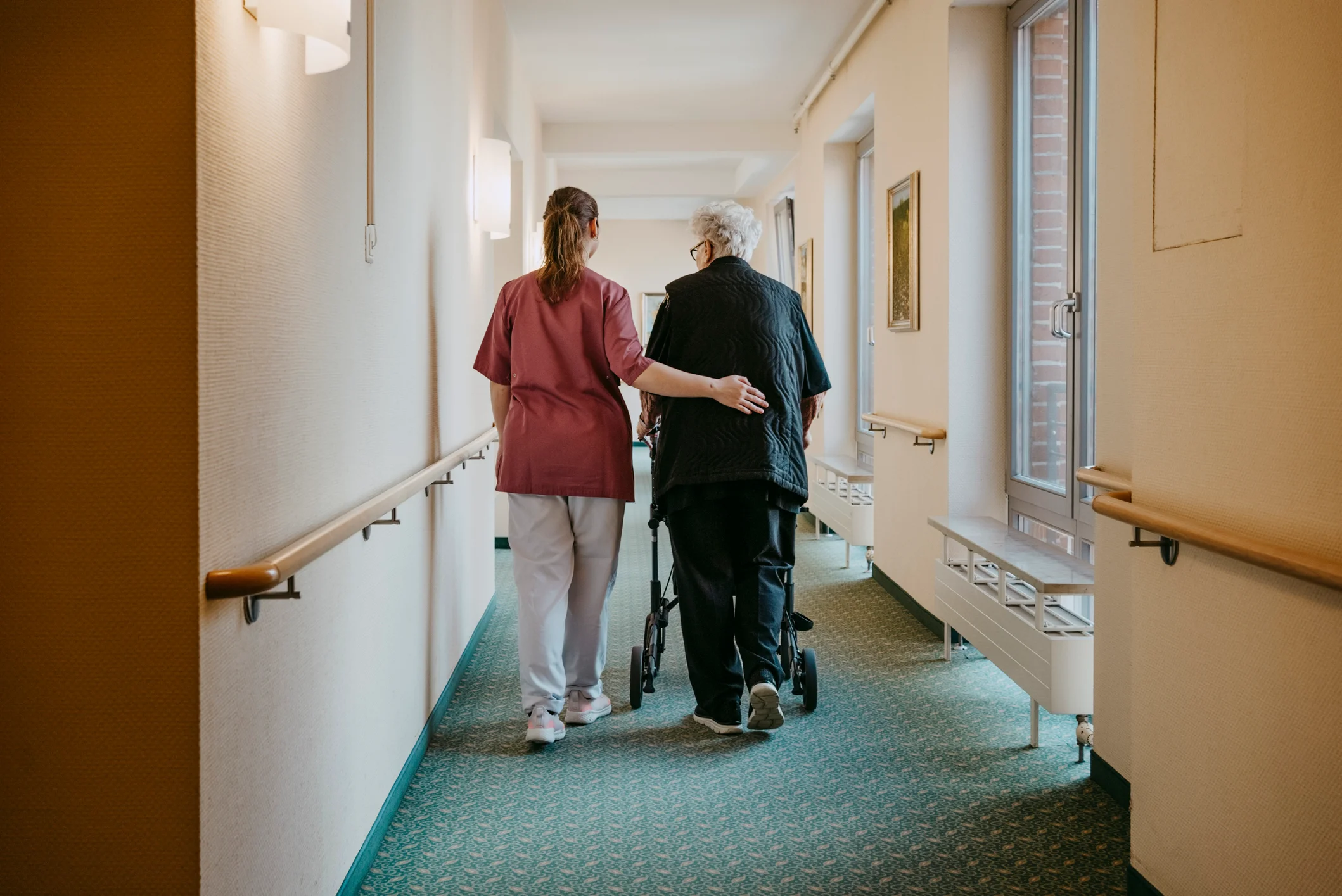 A compassionate nurse helps an elderly resident within a rest home, illustrating the long-term care services paid for by private funds or the NZ Residential Care Subsidy.
