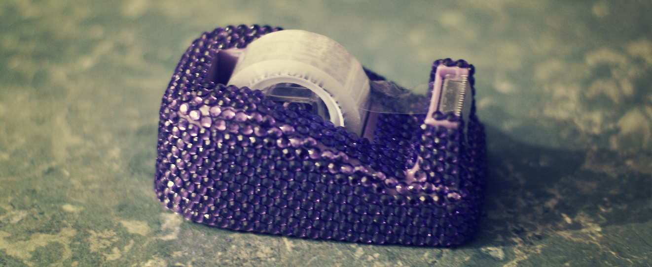 Purple crystal encrusted sticky tape dispenser with a roll of invisible tape in it