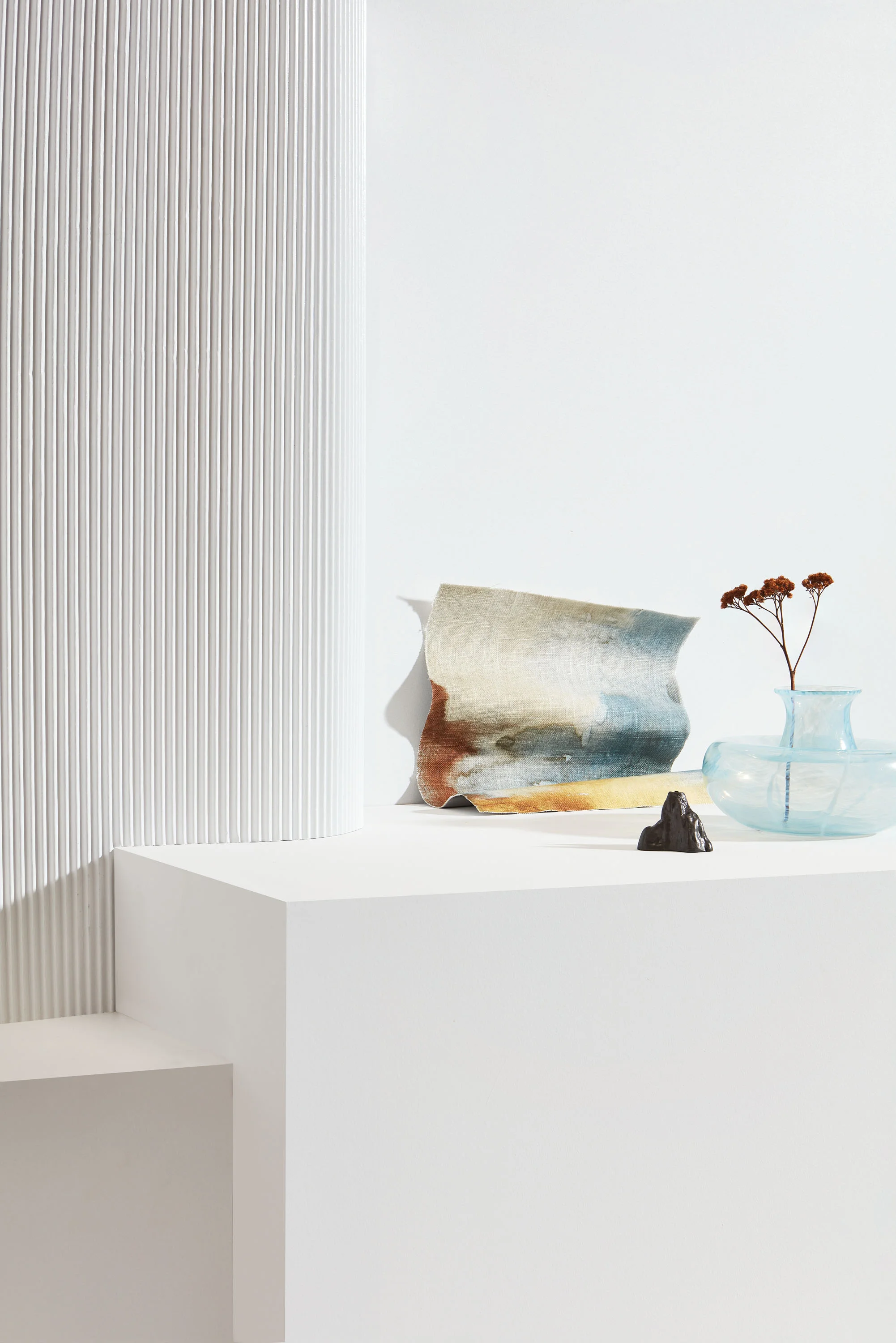 ABOVE: BACKDROP Left plinth and wall in Resene SpaceCote Low Sheen Half Concrete; corrugated pillar in Resene Enamacryl Half Concrete; right plinth in Resene SpaceCote Flat Half Concrete, resene.co.nz. DECORATIVE ITEMS, FROM LEFT Motueka fabric, $65/m, marthas.co.nz. Stone candle holder by Ferm Living, $35, slowstore.co.nz. Feather bowl, $300, monmouthglassstudio.com.