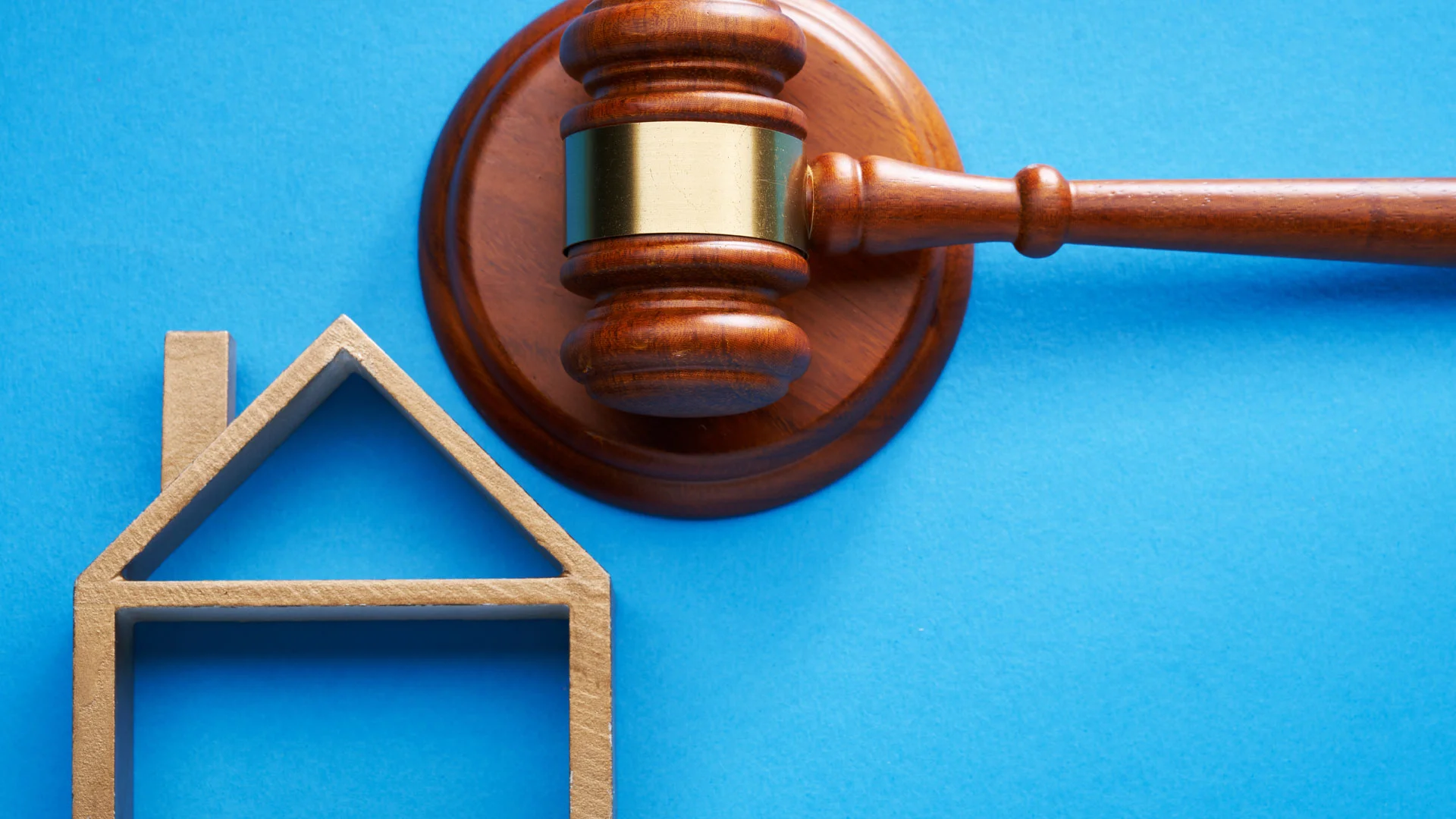 A picture of a hammer and gavel next to the outline of a house.