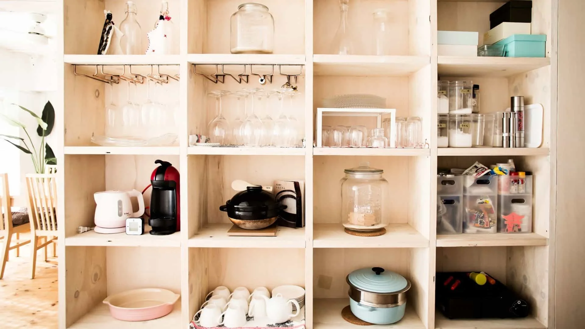 A set of wooden cube shelves filled with wine glasses, coffee cups and other kitchen items.