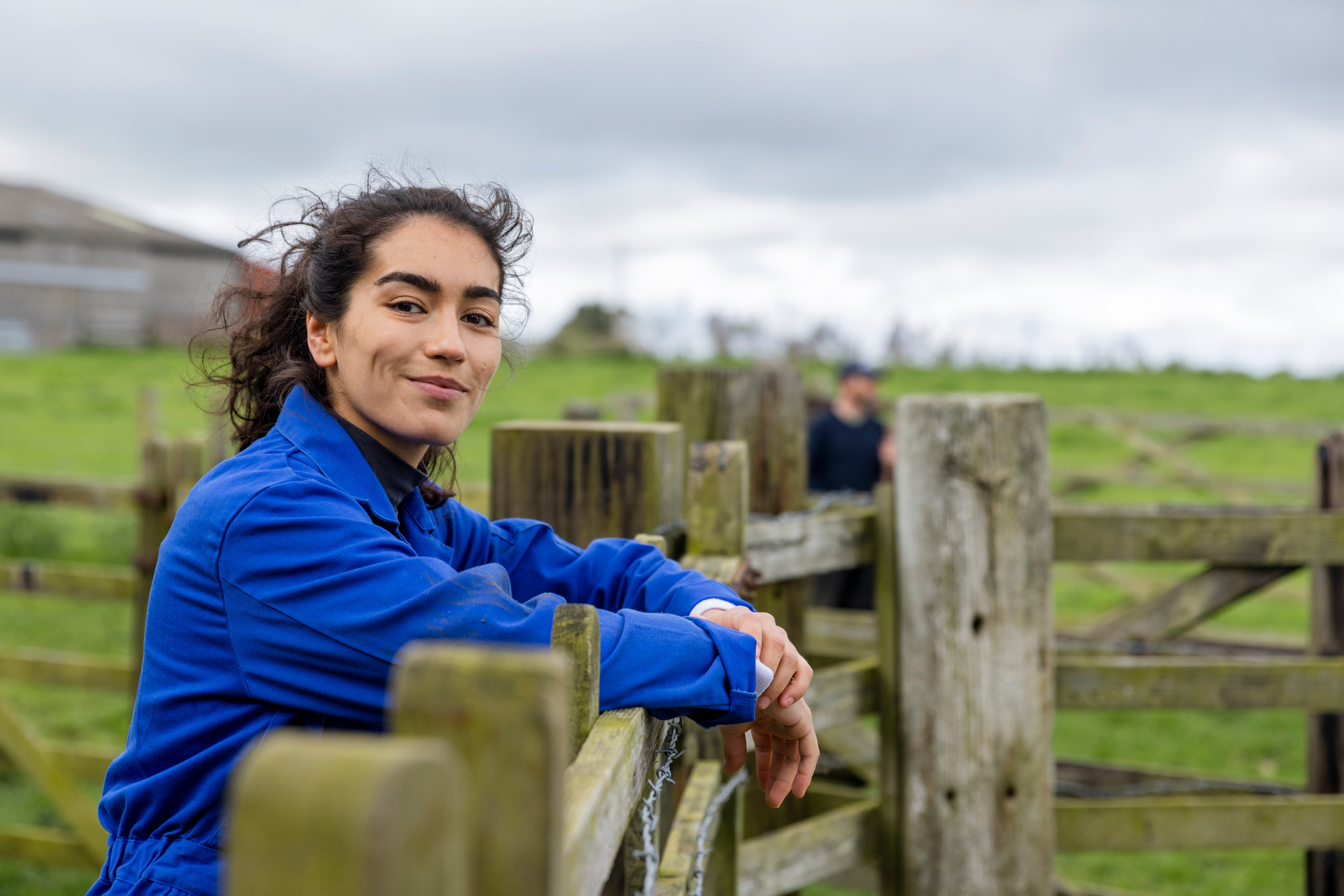 Female farmer leaning over a farm fence