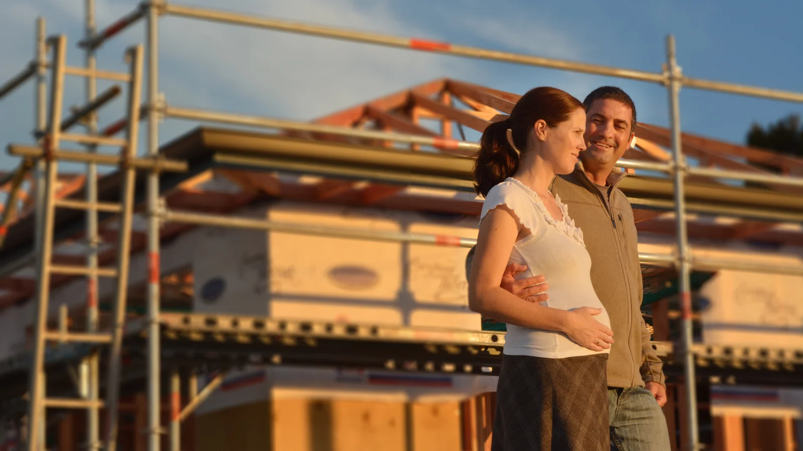 Couple standing in front of home under construction. 