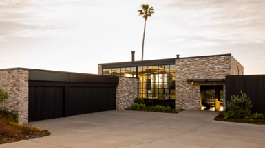The entry elevation combines steel glazing, reclaimed brick, and cedar to create an unexpected warehouse-like aesthetic in the beachside suburb.