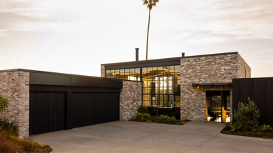 The entry elevation combines steel glazing, reclaimed brick, and cedar to create an unexpected warehouse-like aesthetic in the beachside suburb.