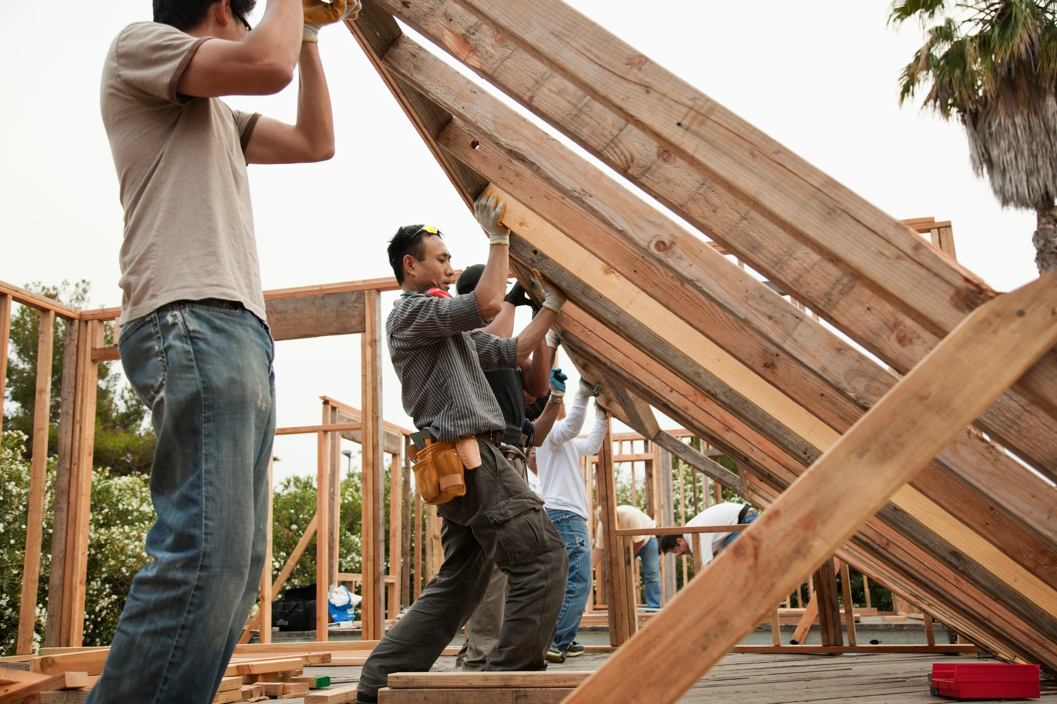 Construction workers lifting house frame.