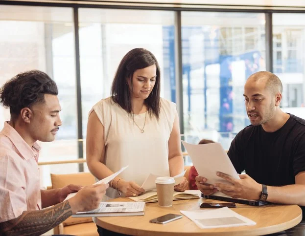 Man with laptop interviewing two women in a cafe.