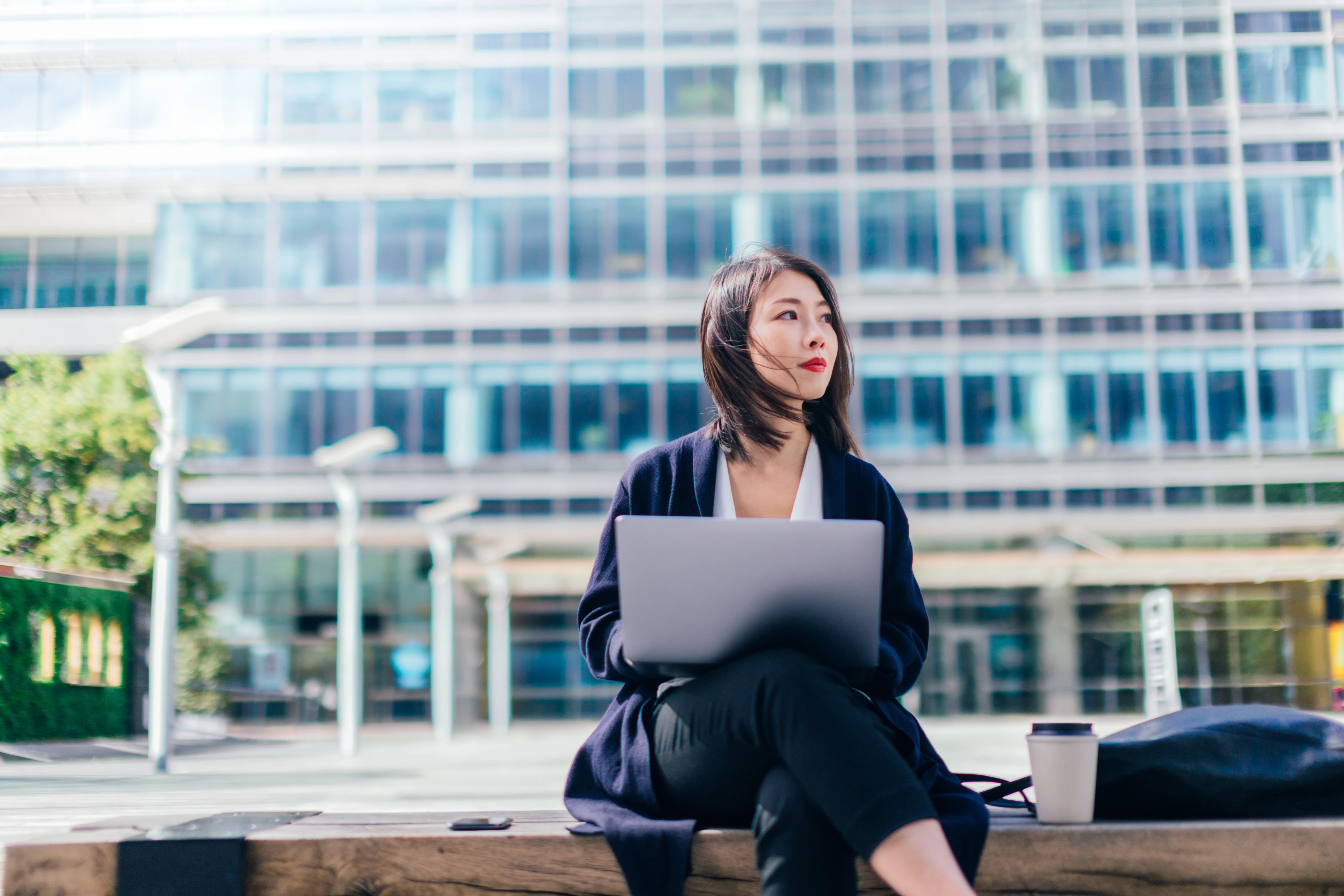 Woman sitting outside a business, considering her job opportunities.