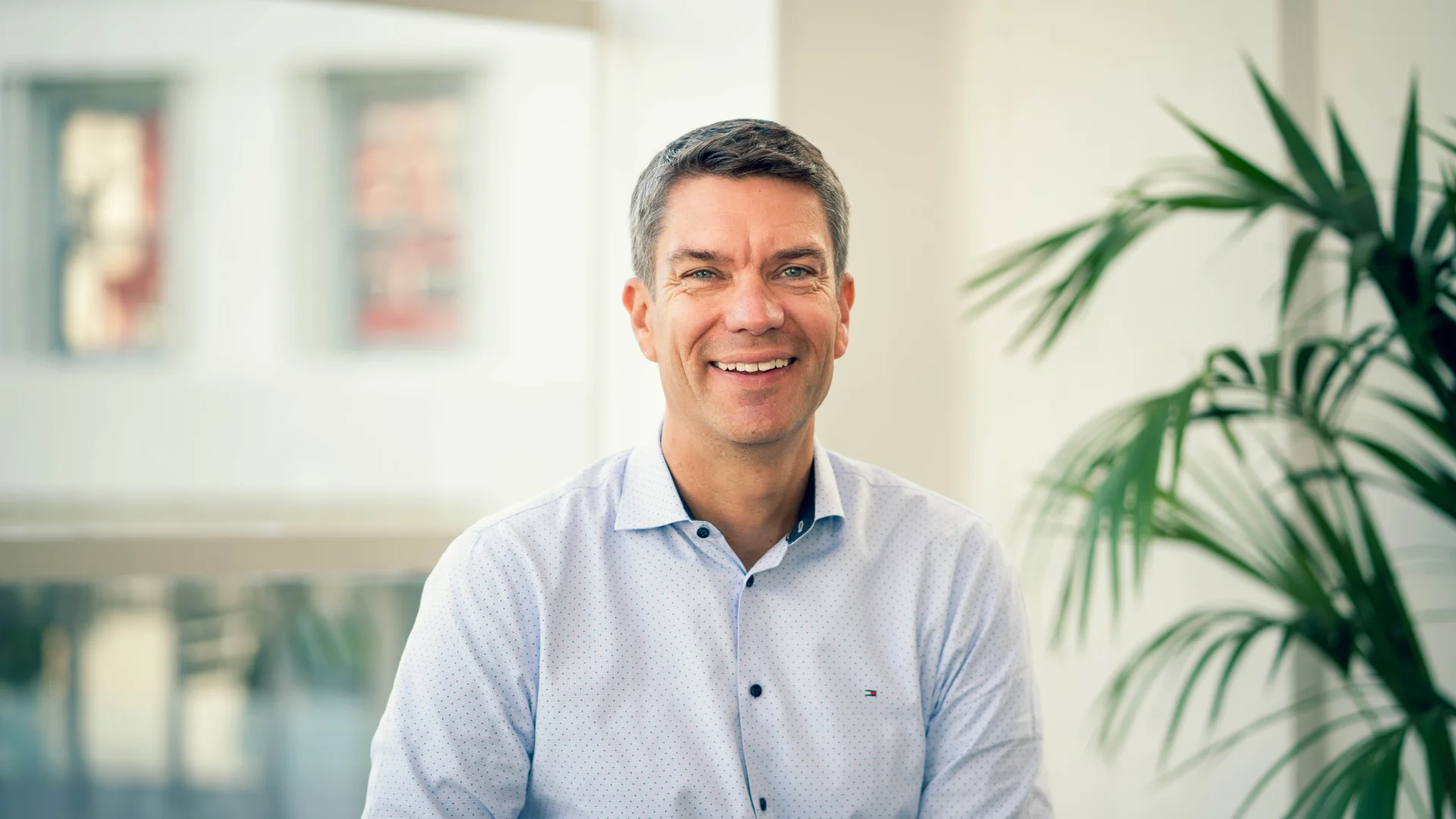 Photo of Anders Skoe Trade Me CEO in an office in front of a large window and white wall.