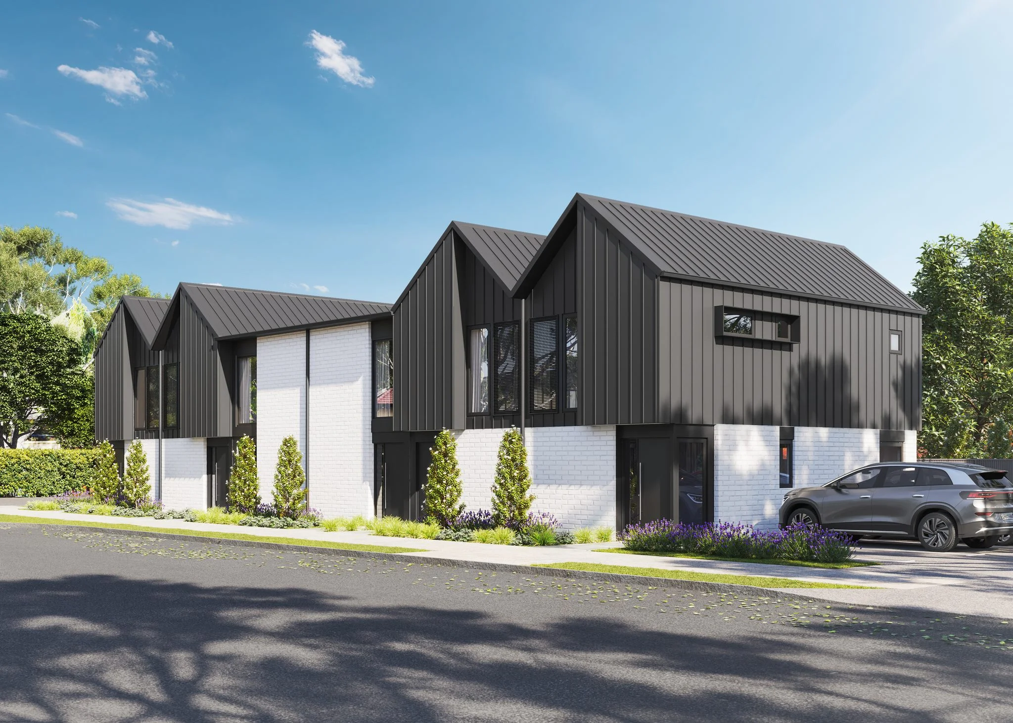 Modern townhouses with dark gabled roofs and white brick walls line a quiet suburban street.