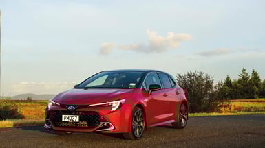 Red Hybrid Toyota Corolla front end stationary on road.