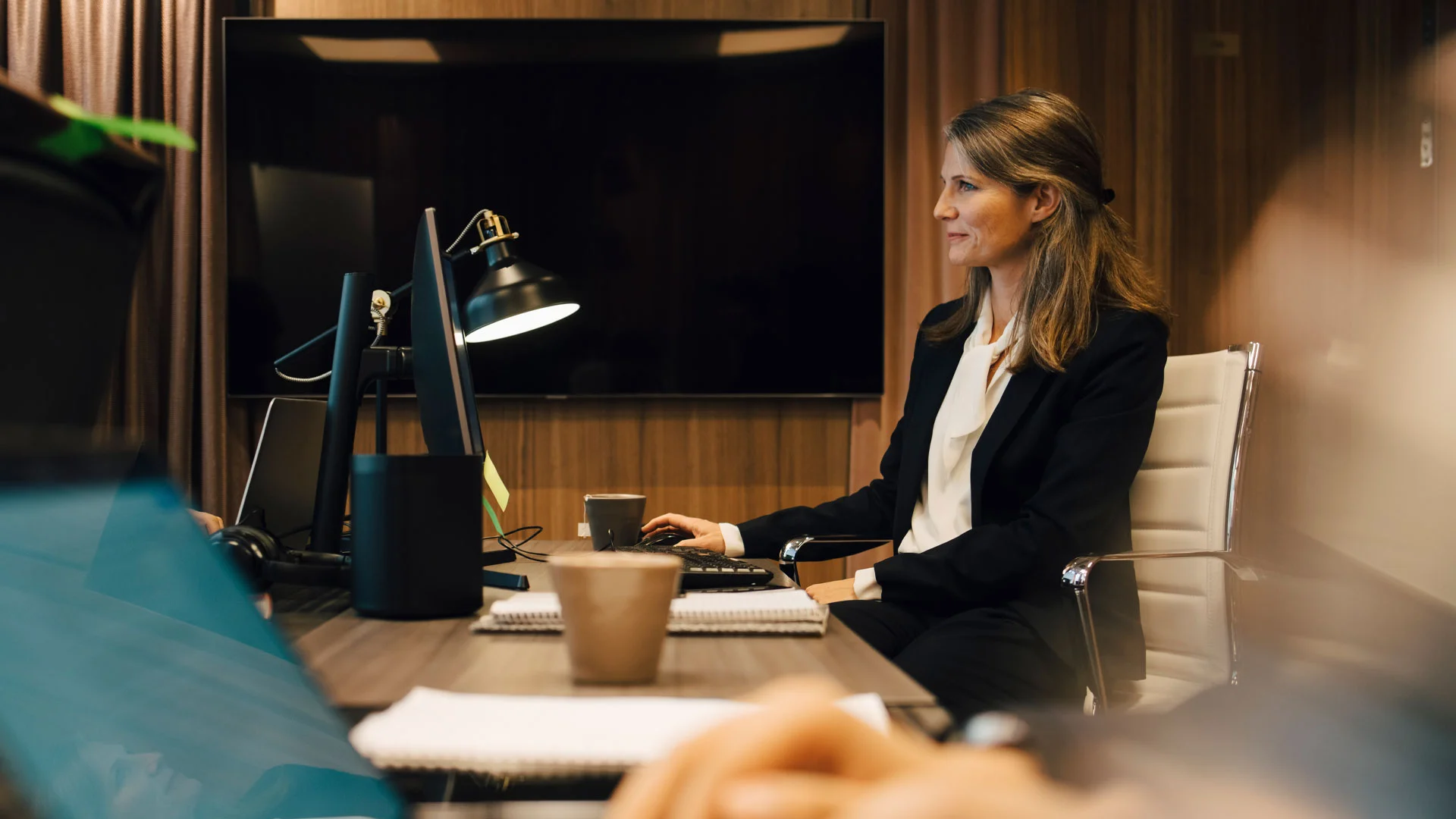 Solicitor working late in her office at night, smiling at her computer.