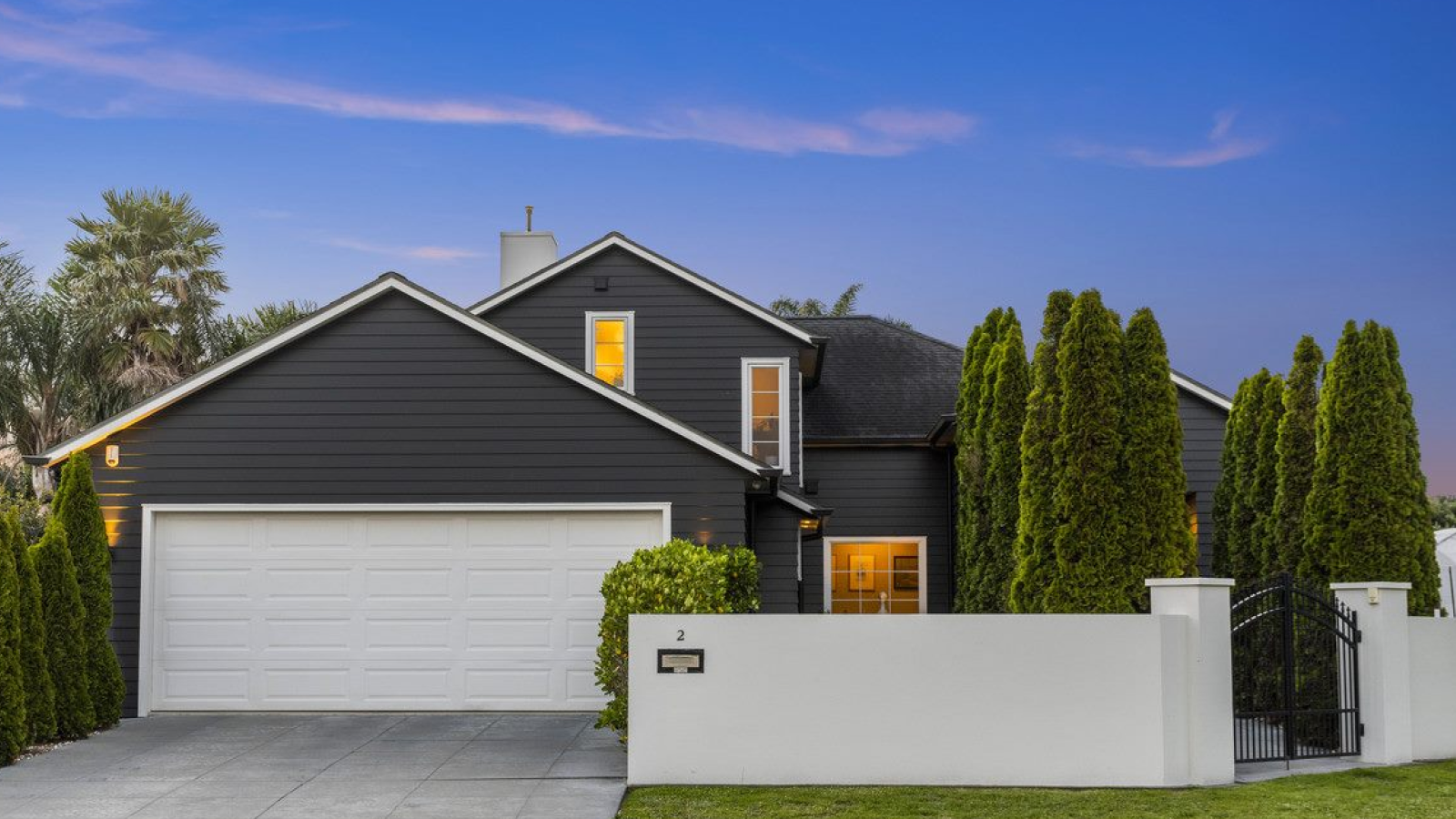 Grey house with a white garage and green trees
