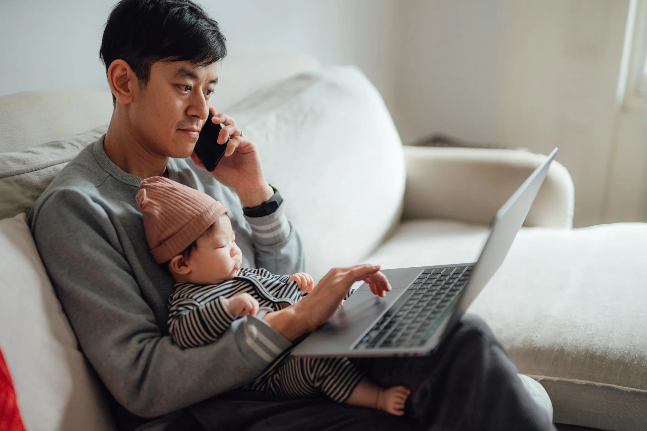 Dad holds his baby while on the phone