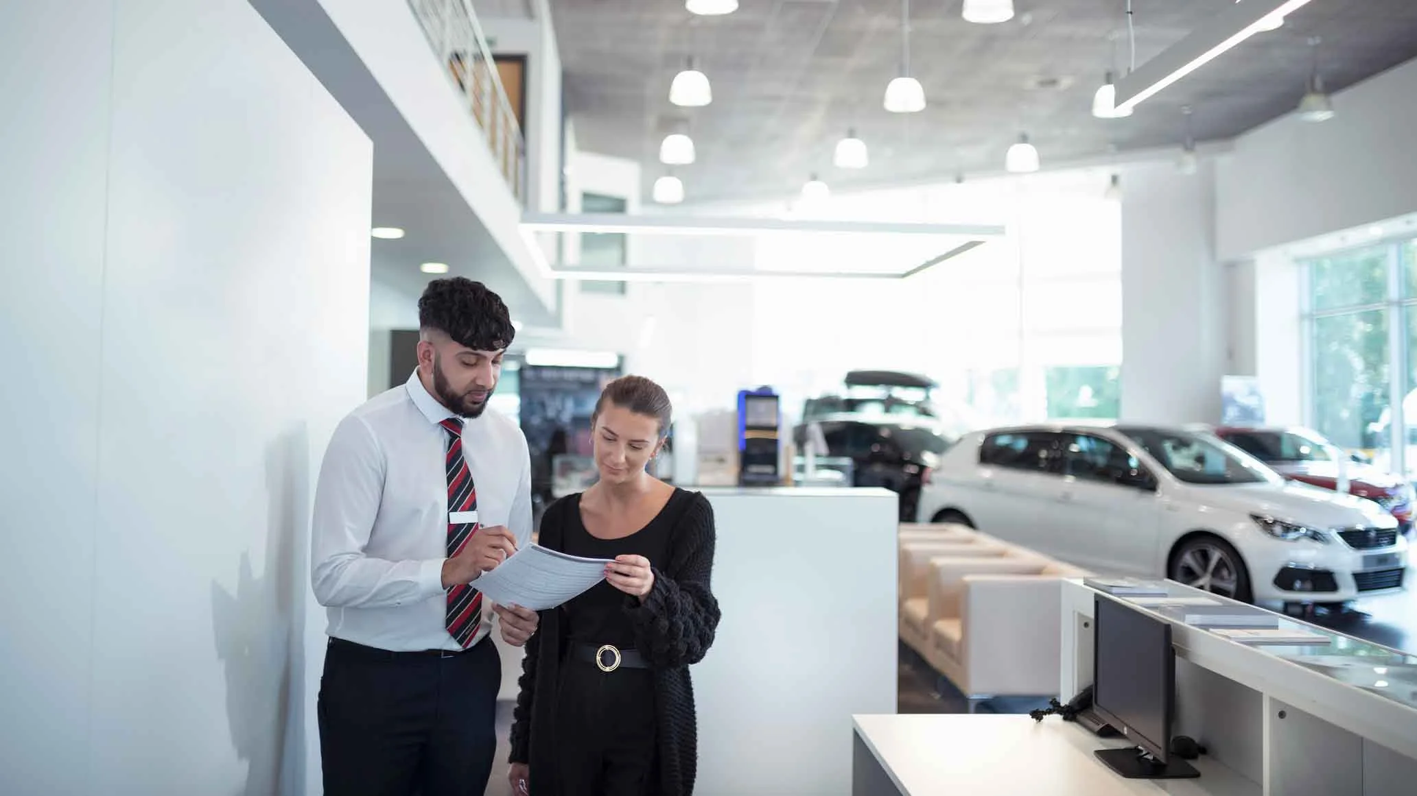 Employees at car yard looking at paper work.