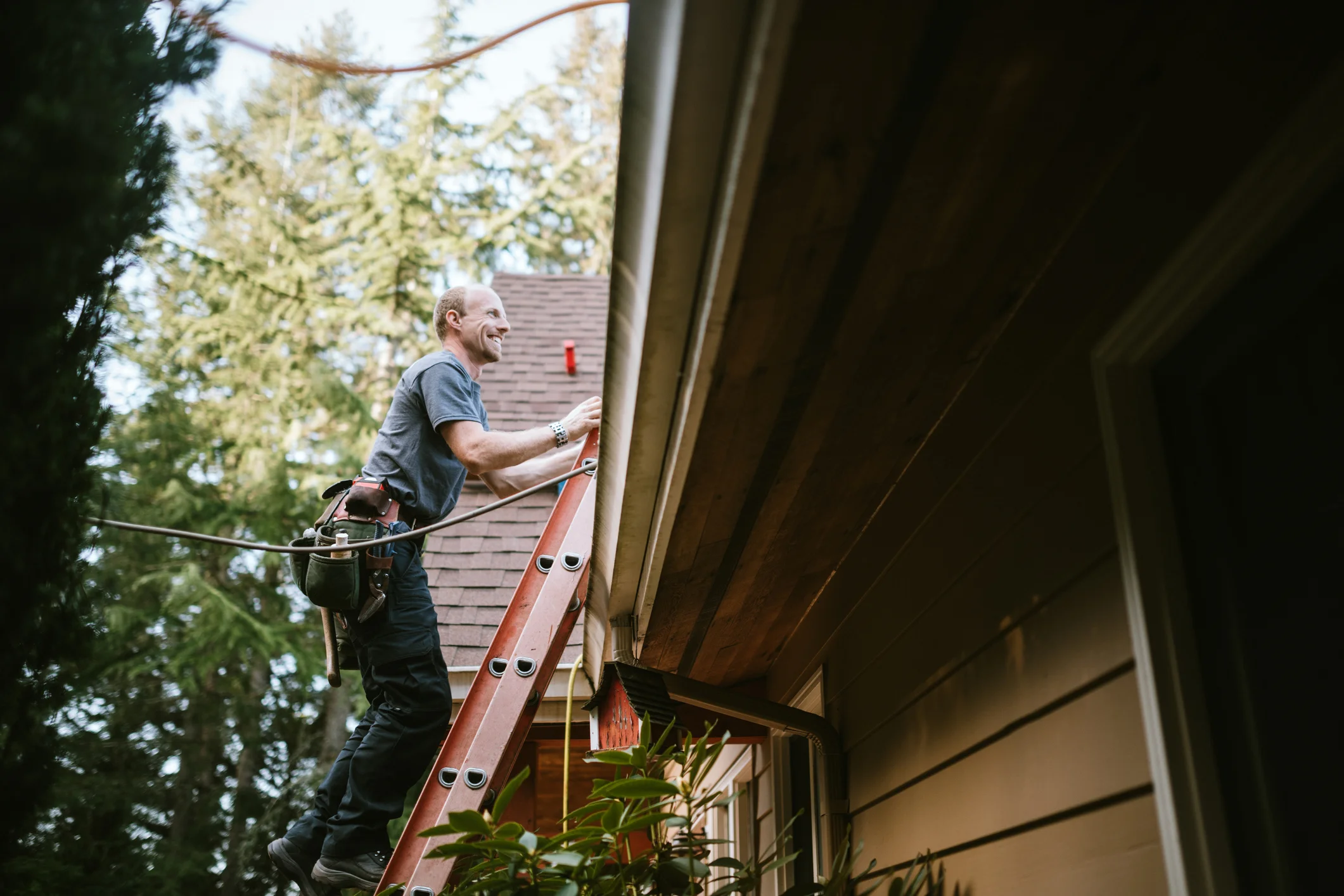 Man on a ladder looking at the roof