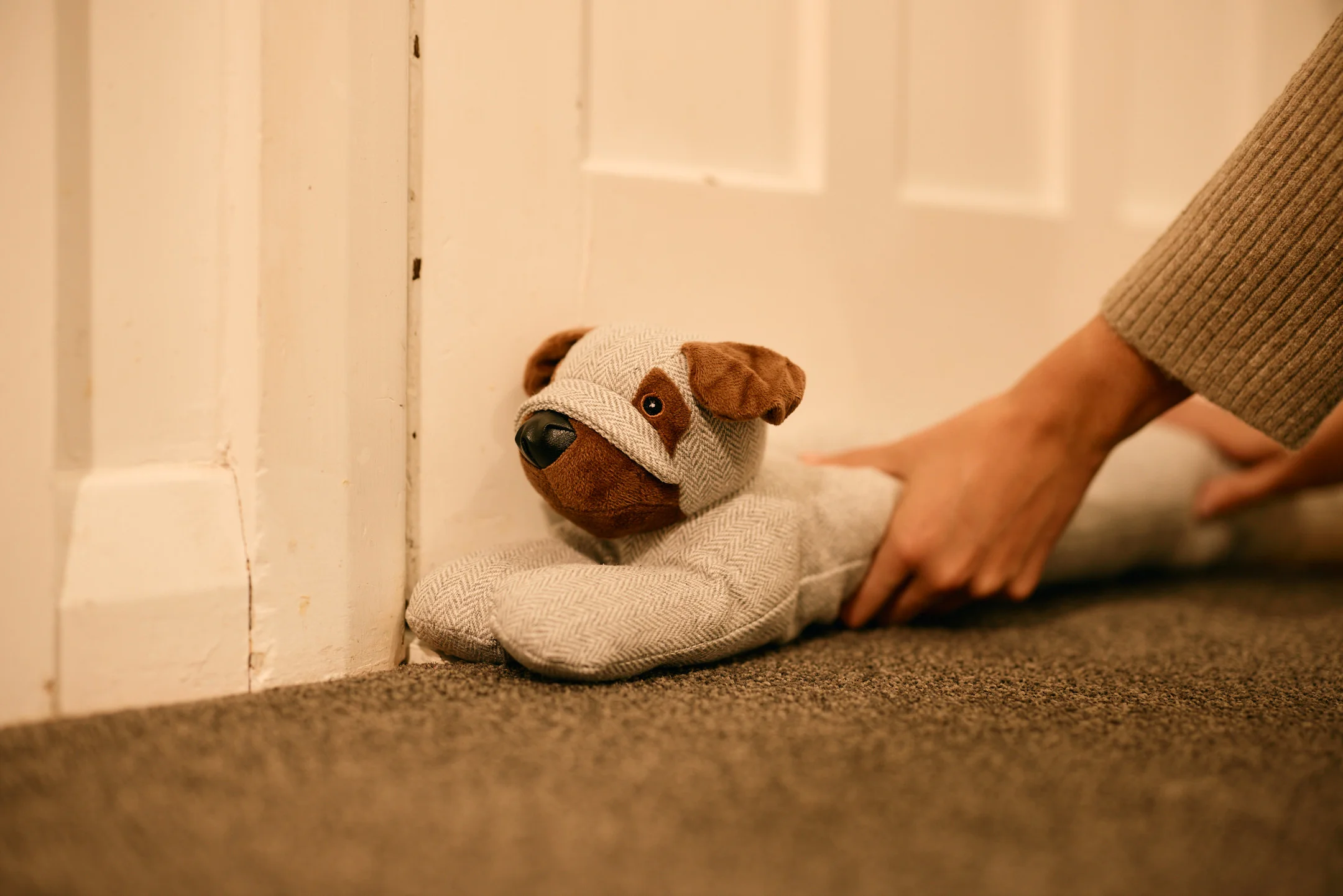 Dog shaped door stopper being placed in front of a door