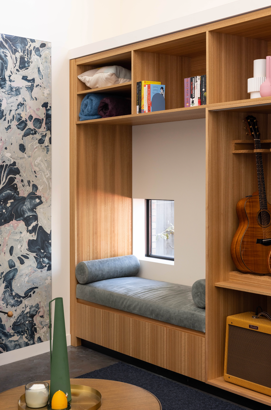 A cozy window seat created by a large window, featuring soft cushions and storage underneath, perfect for relaxation and natural light.