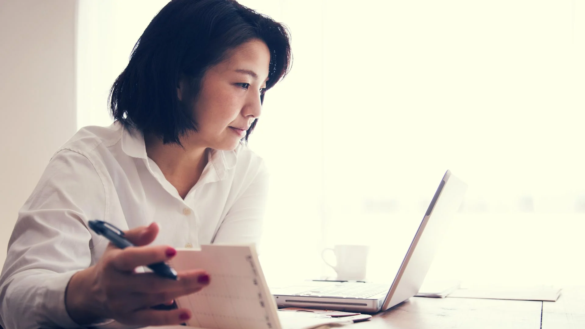 A woman making notes at a desk.