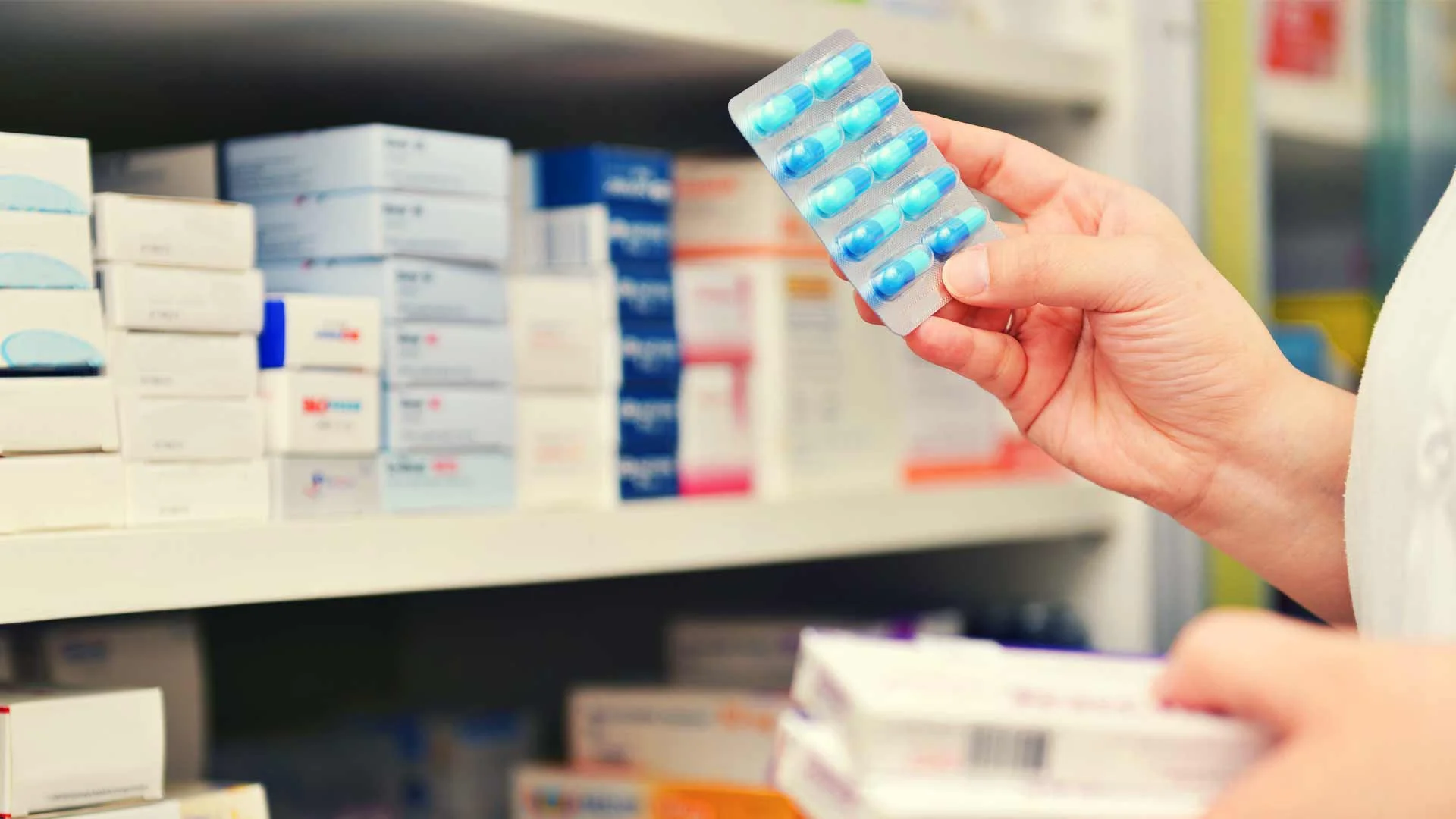 Pharmacist selecting medicine from a shelf.