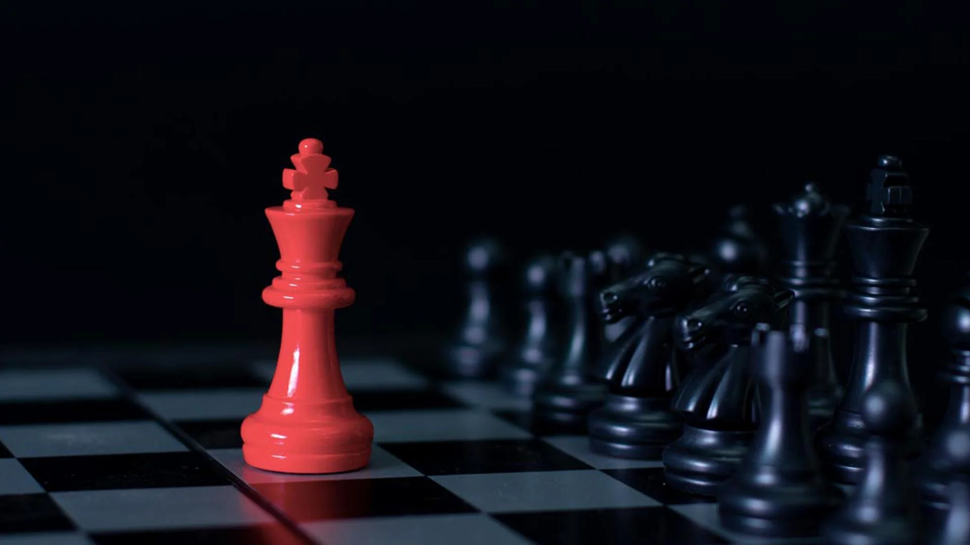 Pictures of chess pieces, where one is coloured red to symbolise it standing out from the other black pieces.