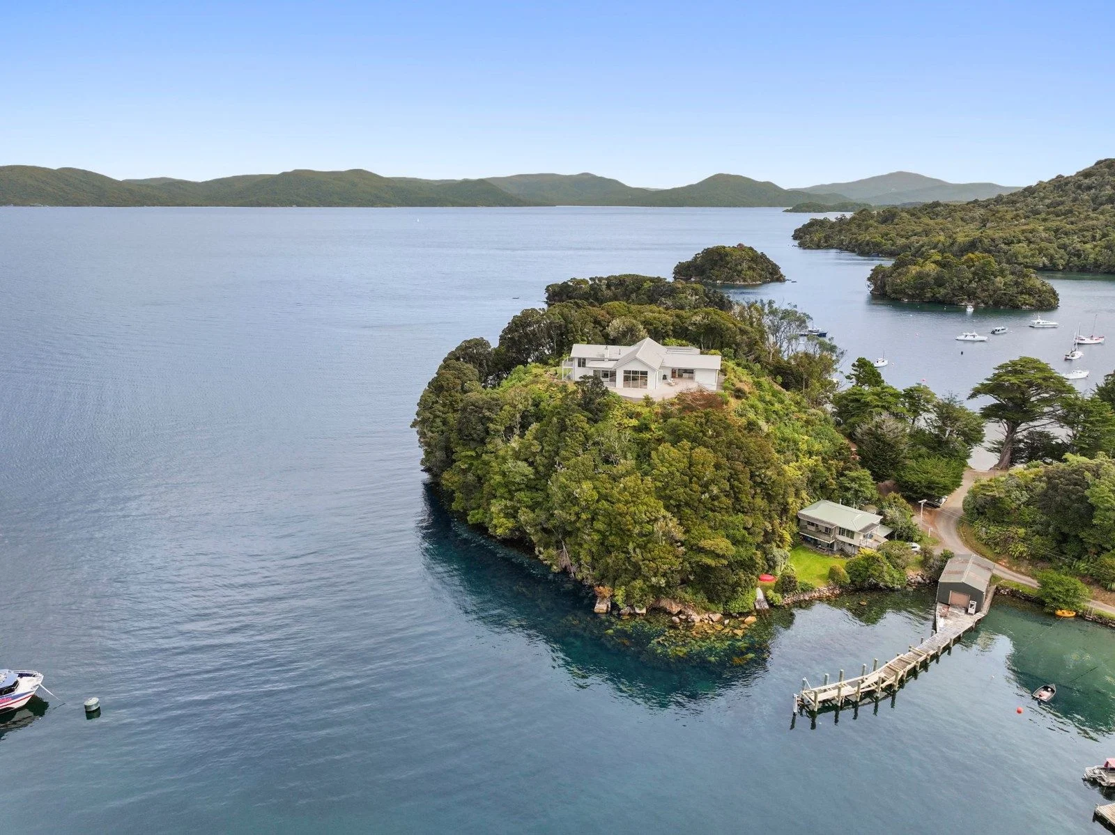 A large house sits on top of a hill surrounded by the vast water of the South Island of New Zealand.