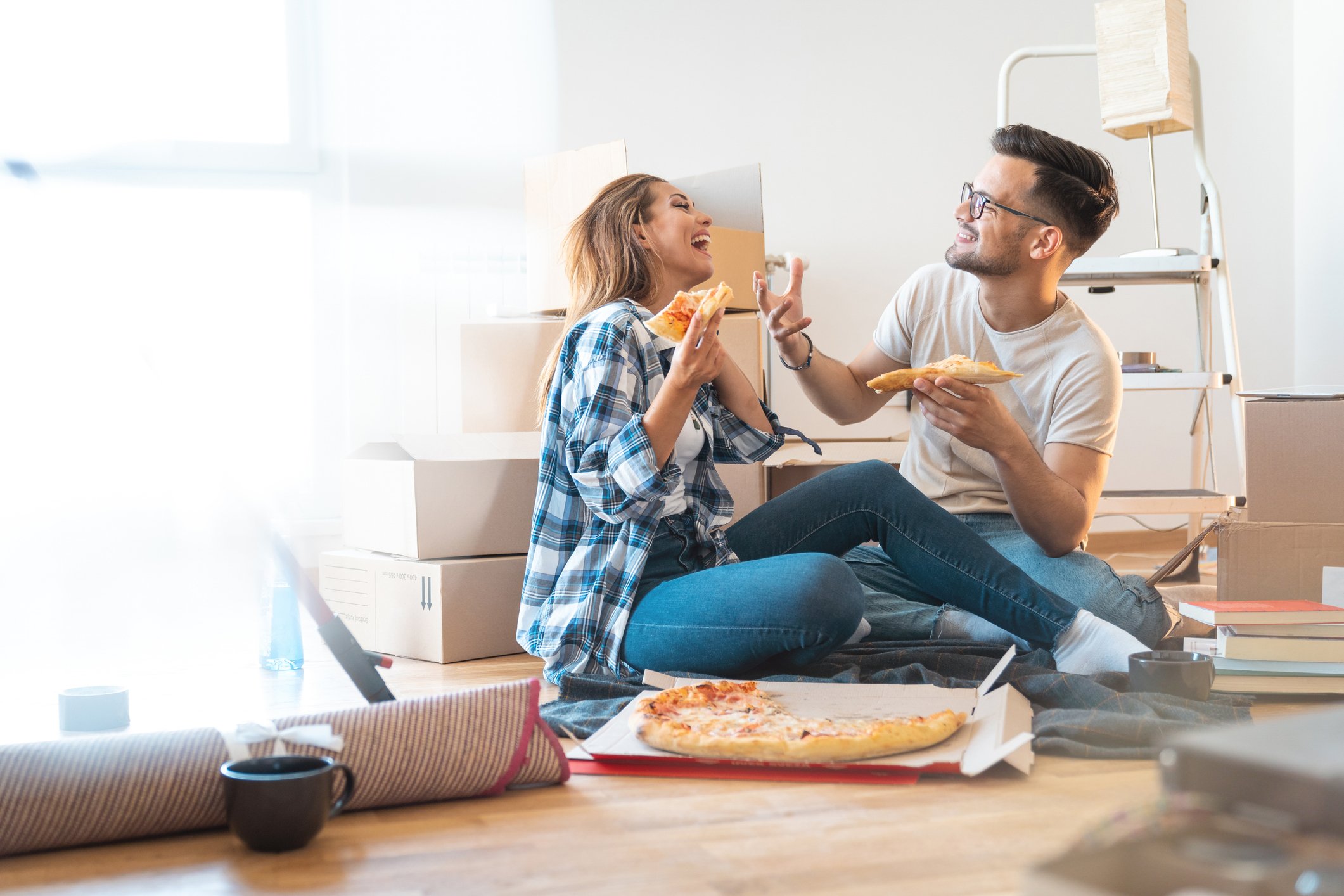 Couple eating pizza on the floor of their new home