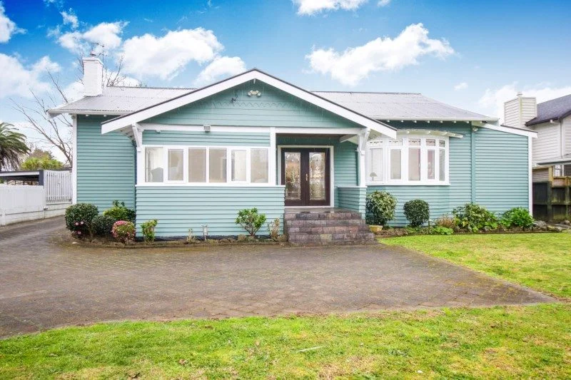 Font view of a quaint turquoise home with white trim