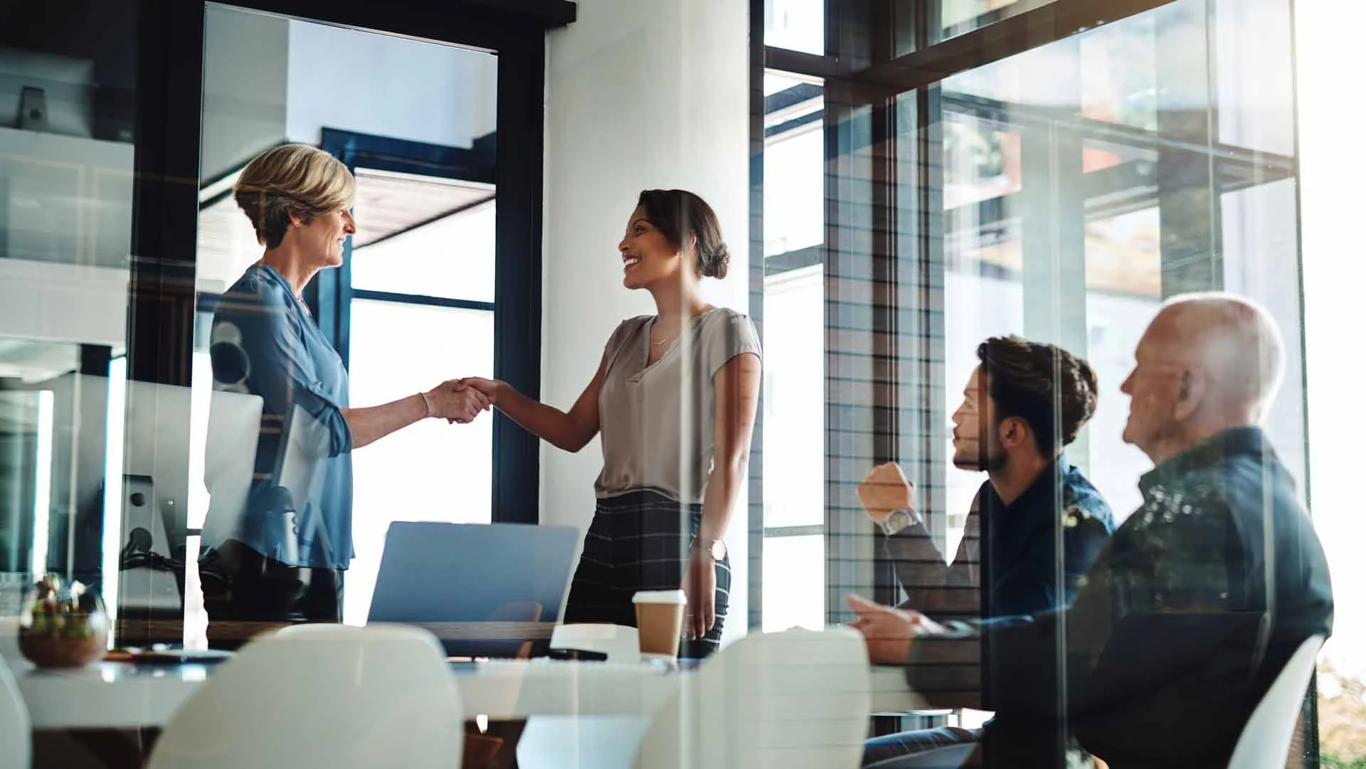 Two women shaking hands to make an agreement in an office.