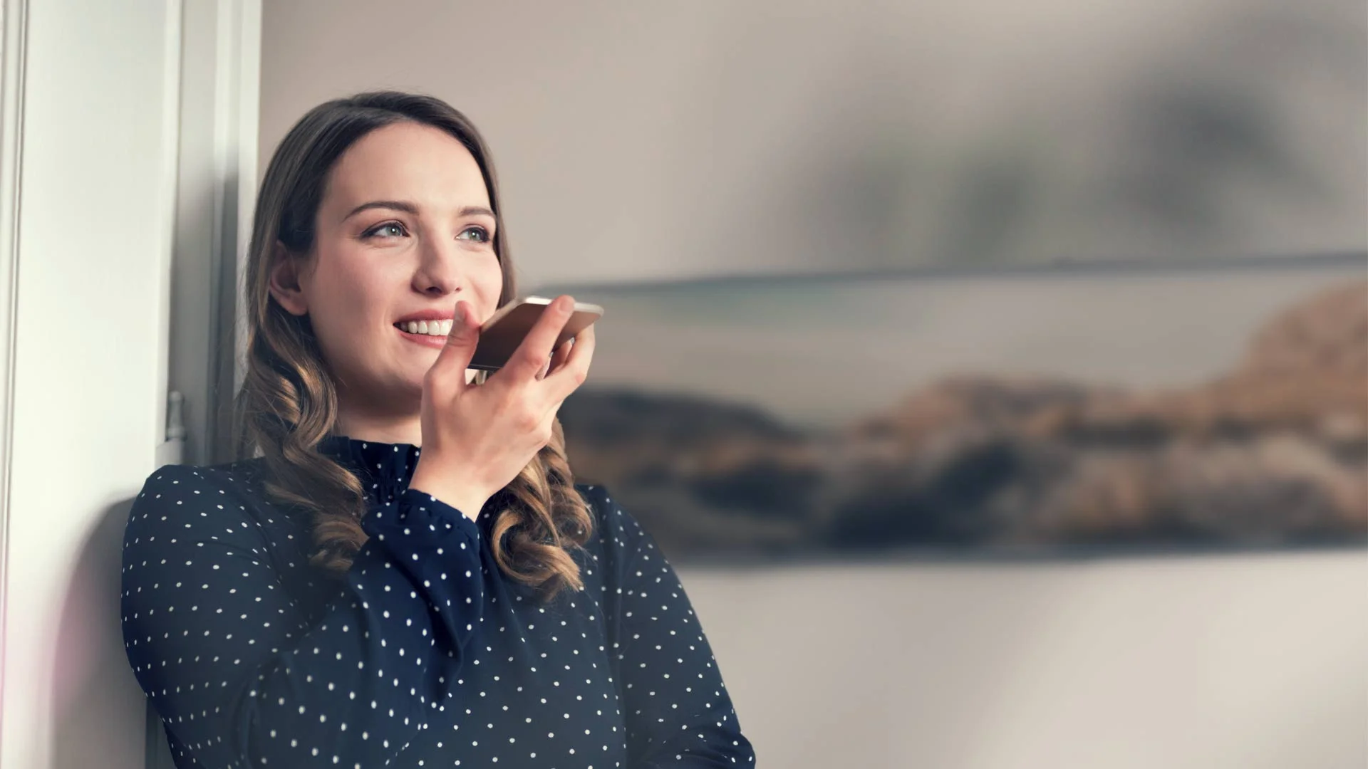 Woman smiling while on speaker phone to a hiring manager.