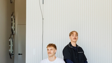 Matt (left) and Dan in their living space, on their Muse sofa by Sarah Ellison, with a trio of Florence mirrors by McMullin & Co and a Parentesi lamp by Flos from ECC suspended beside them