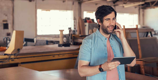 Man on the phone holding a tablet talking to a buyer about some items he is selling on Trade Me.