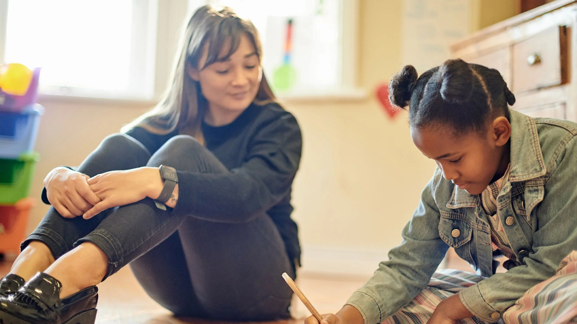 Art teacher watching over a student who is drawing in an classroom.