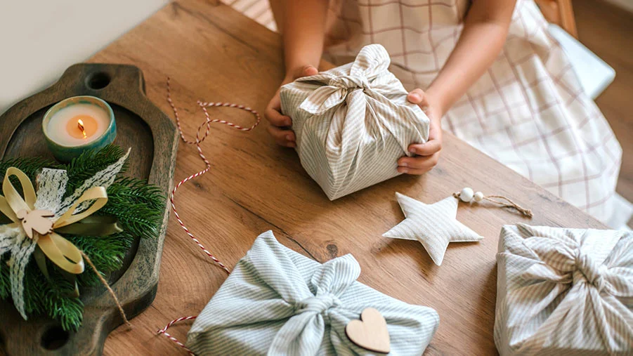 Girl wrapping presents in eco-friendly cloth in preparation for