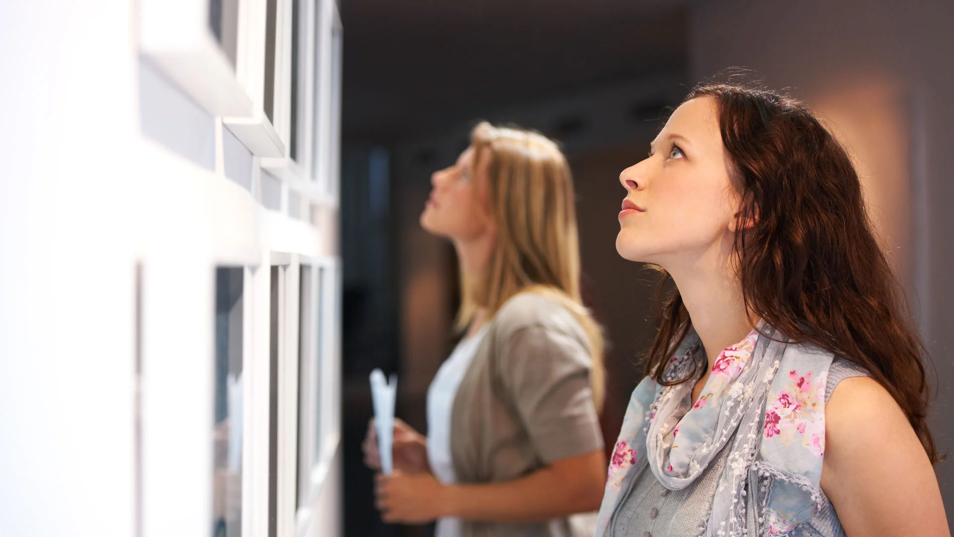 Art critic looking closely at a piece of art in a gallery exhibition.