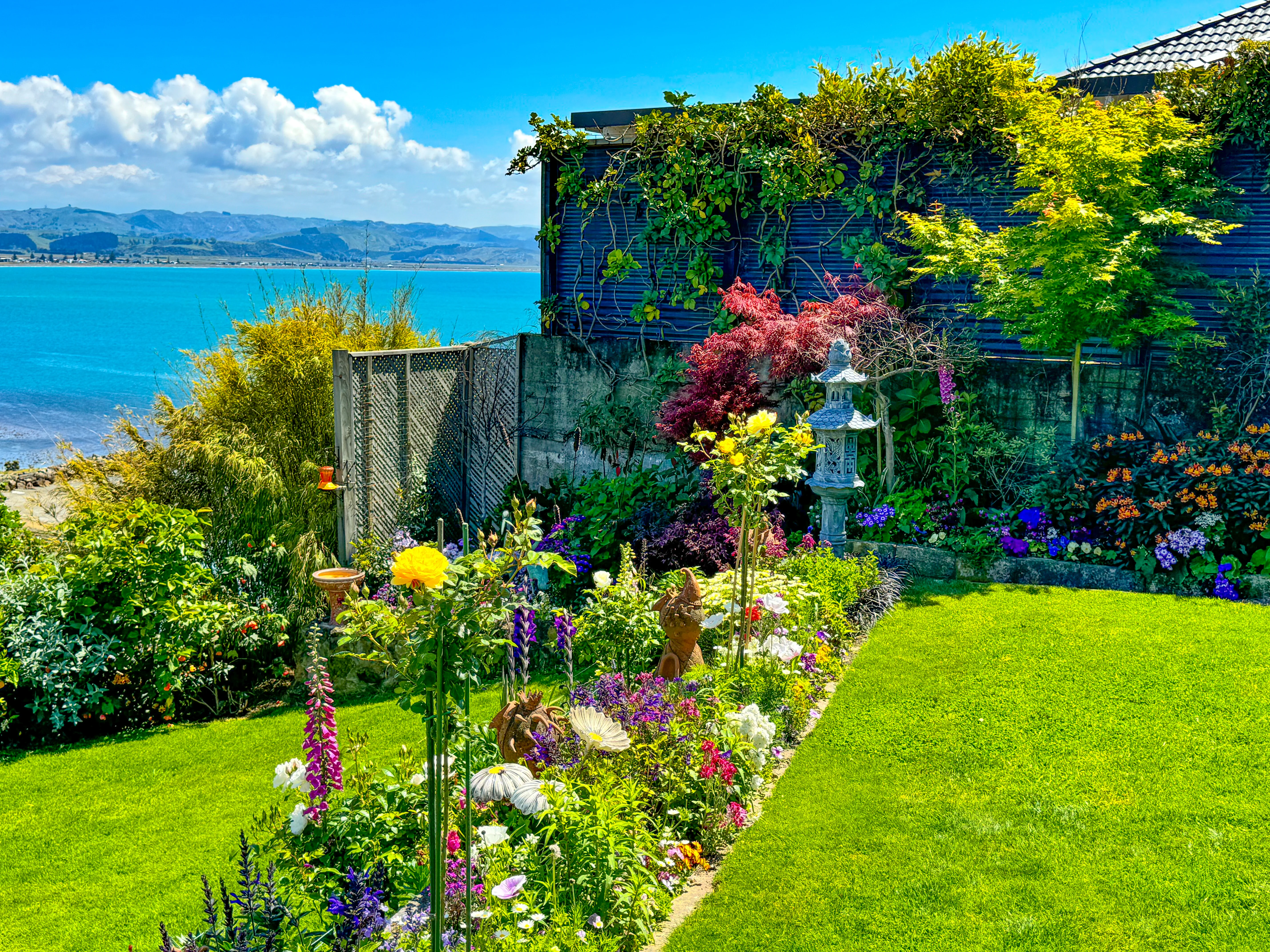 Well maintained lawn with borders filled with colourful flowers. The garden overlooks the ocean and the mountains