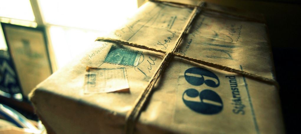 package wrapped in brown paper, tied with brown string, stamped with international packaging stamps