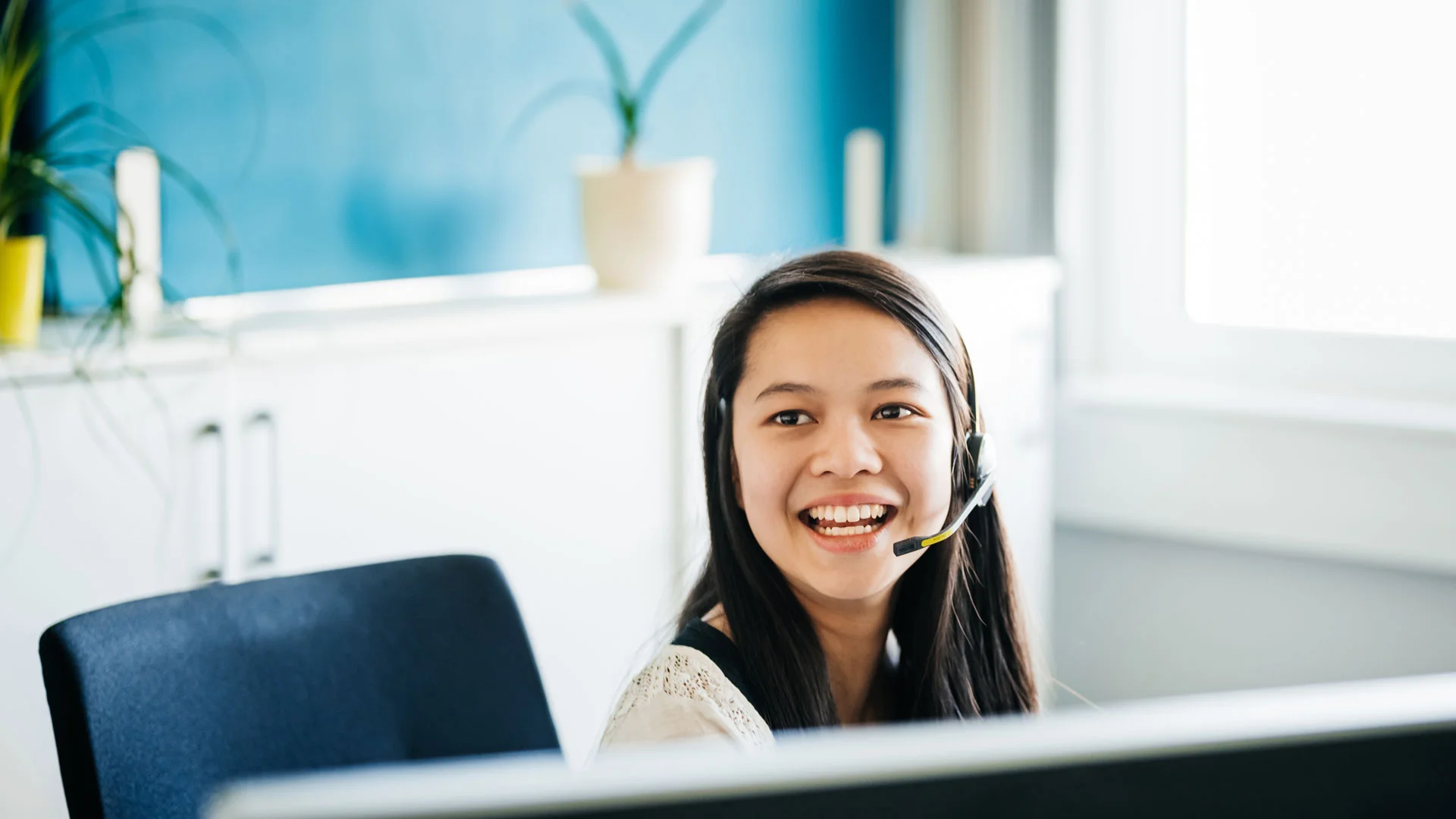 Customer service representative talking on a headset in an office.