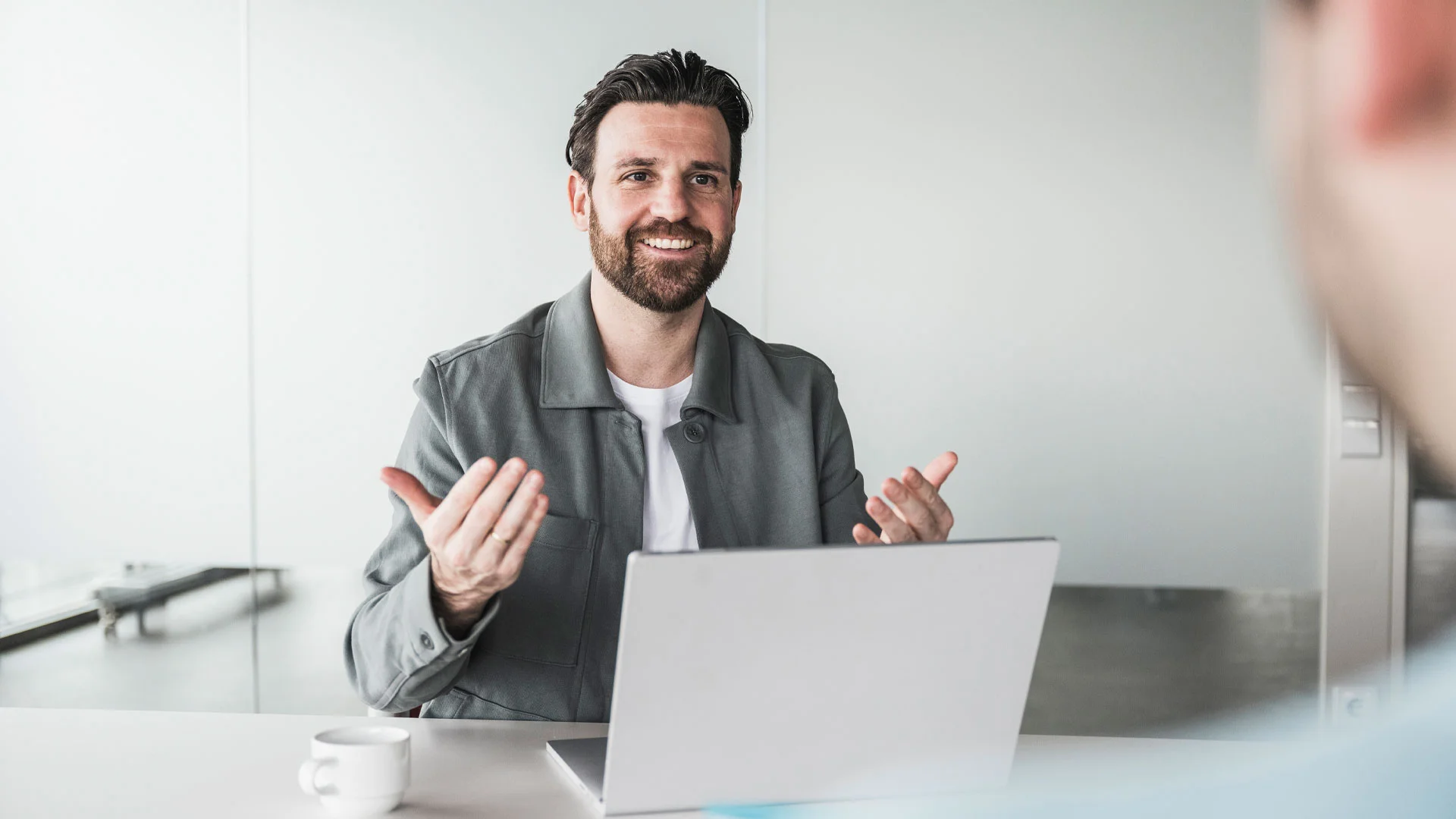 HR employee behind a laptop explaining something to a co-worker.