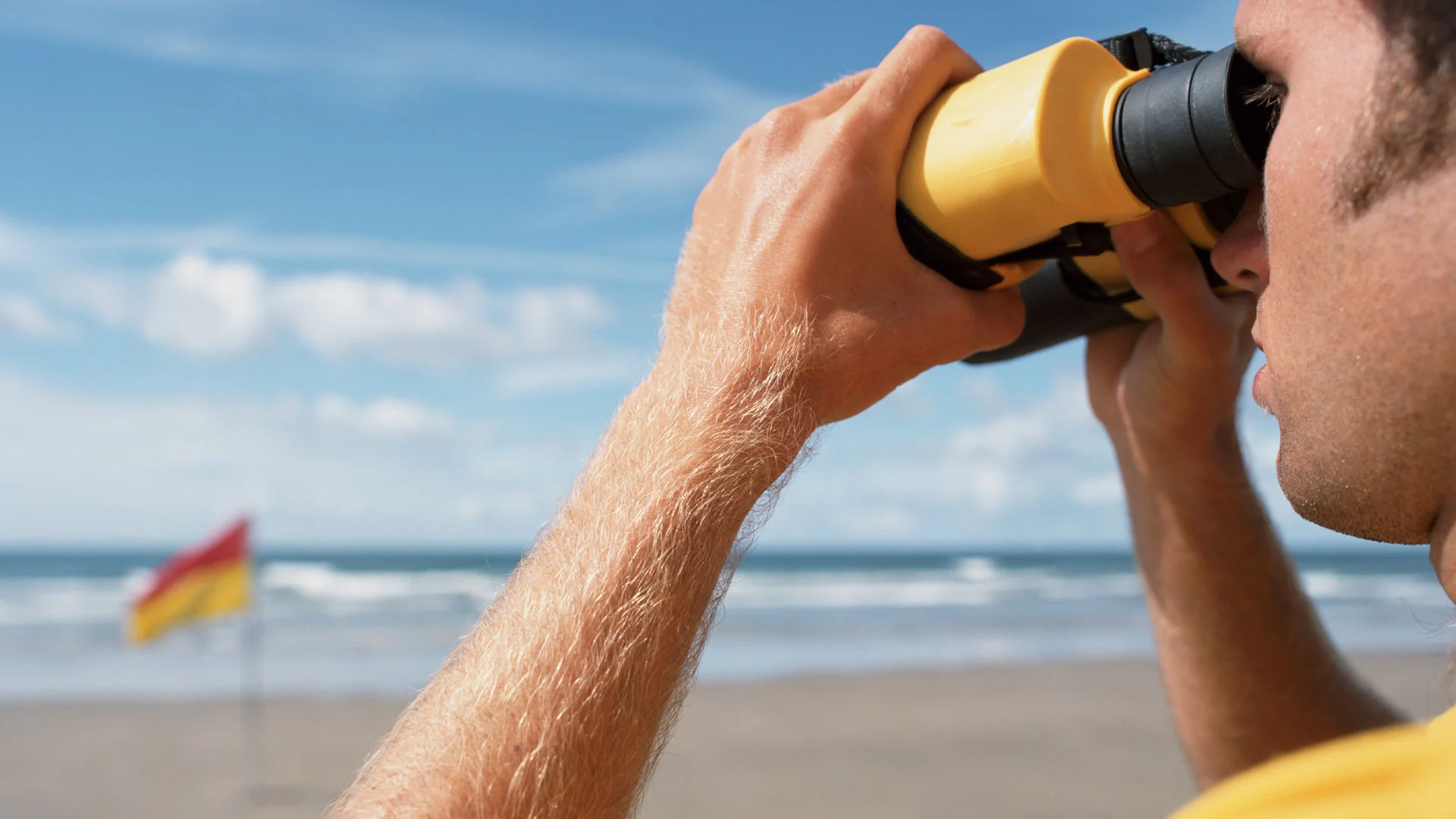 Lifeguard on a beach in New Zealand scanning the water with their binoculars.