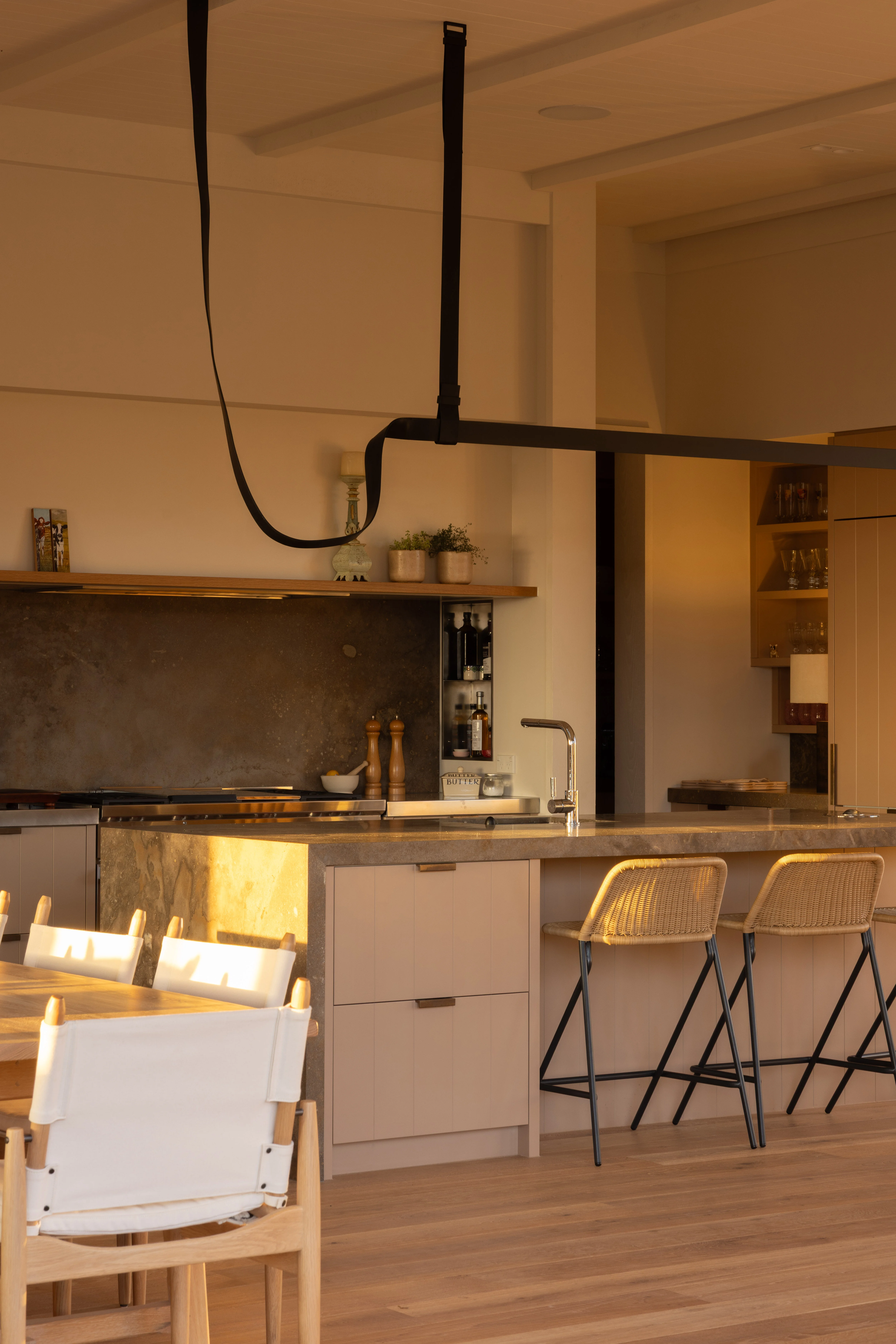 Pierre de Varennes honed limestone features on the splashback and island bench in the kitchen, alongside custom V-grooved cabinetry painted Aalto Eton Cream and made by Molloy Joinery with handmade handles from BlacksandBronze. The black leather Belt pendant, designed by Ronan and Erwan Bouroullec for Flos, is a defining touch and Feelgood Designs Kakī barstools get frequent use when Judith is entertaining.