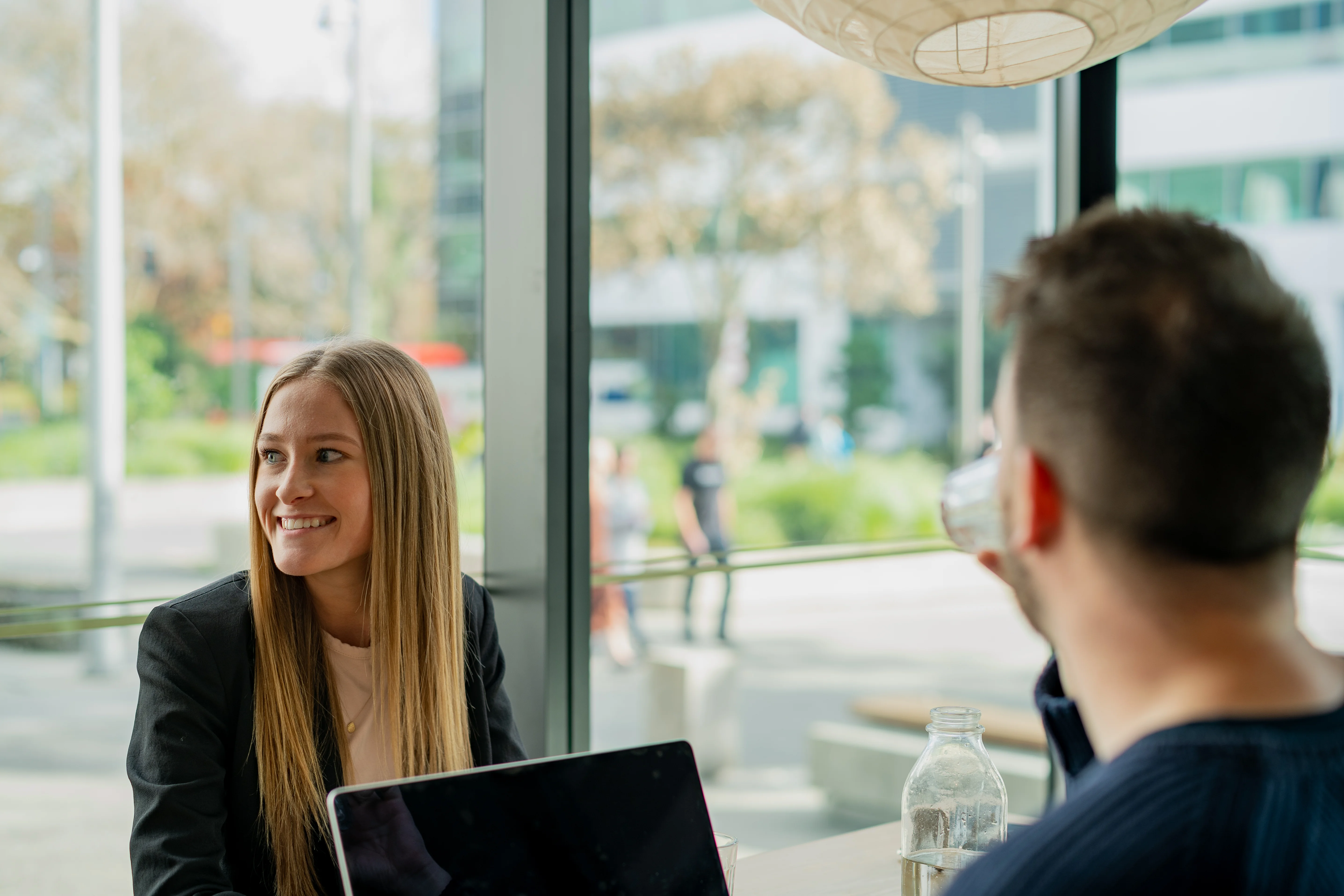 Man with laptop interviewing a woman at a cafe.