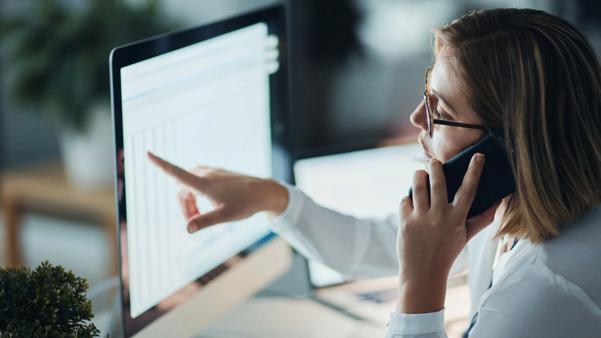 Female applicant reading a salary guide online while talking on the phone.