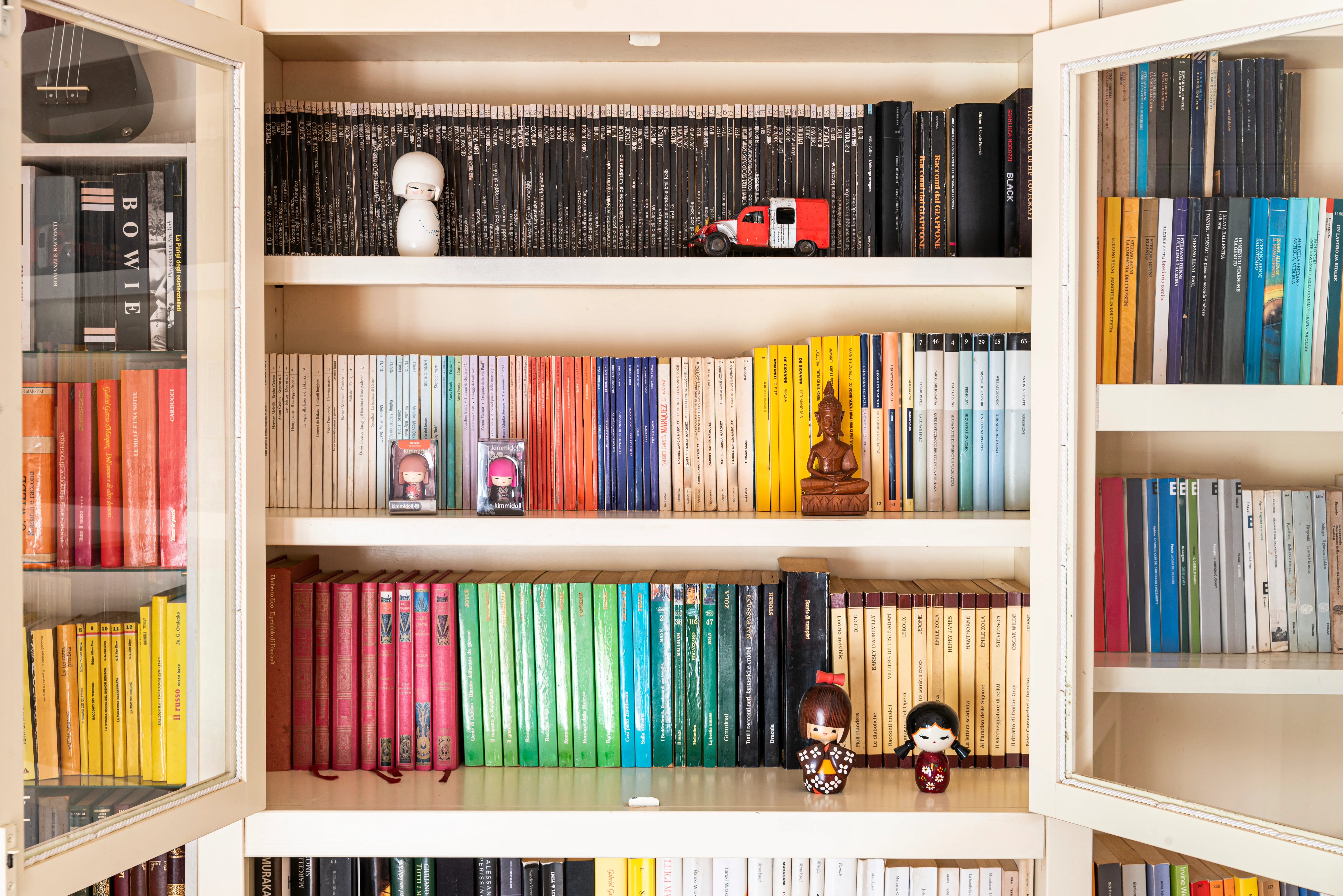 Colourful bookcase decorated with different small ornaments 