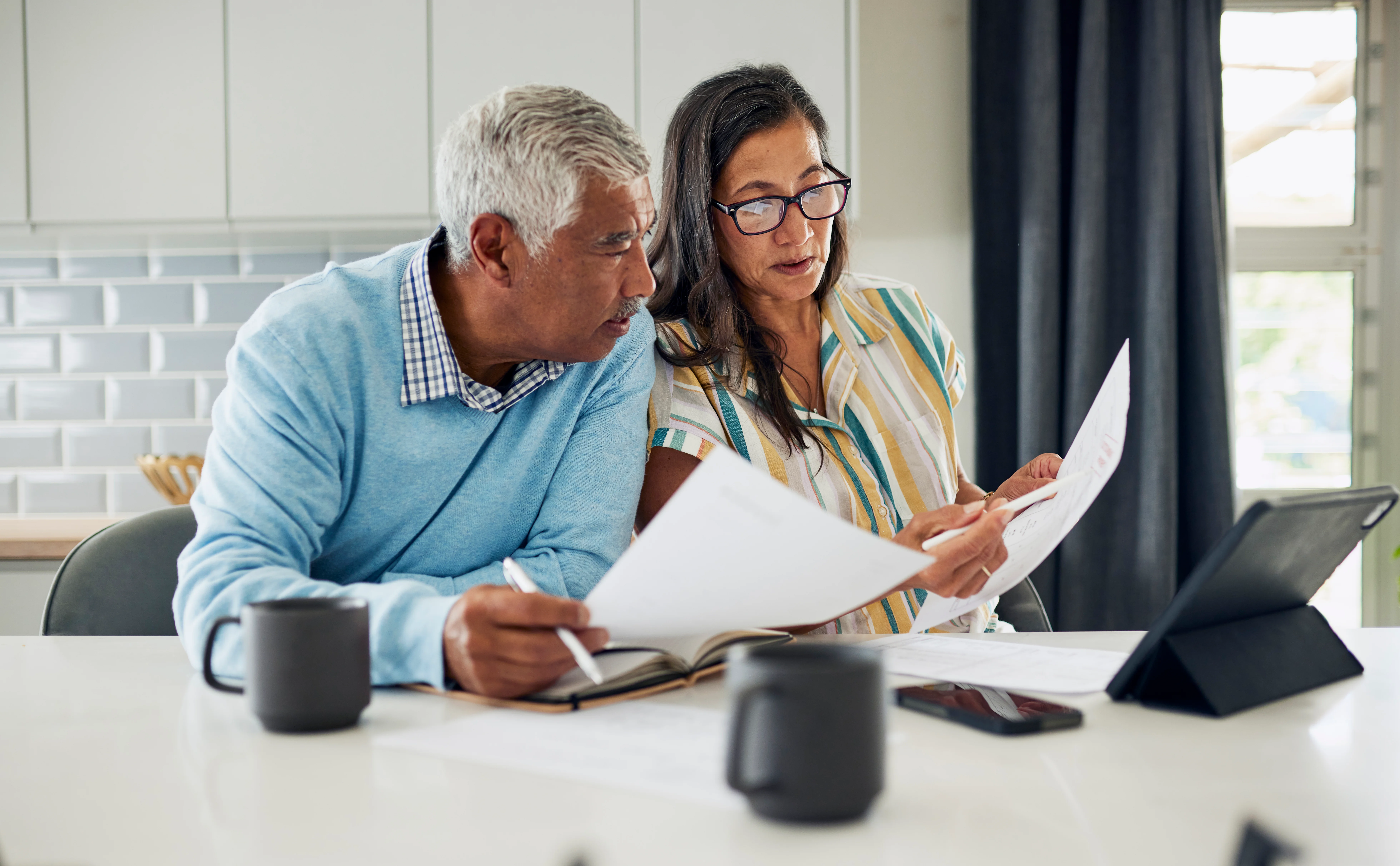 A couple is sitting at their kitchen table reviewing property documents.